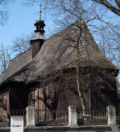 Zdjęcie nr 21: Kościół orientowany, pierwotnie na rzucie krzyża łacińskiego, jednonawowy, z kaplicami bocznymi od północy i południa, z prezbiterium prostokątnym zamkniętym wielobocznie. Obecnie w miejscu drewnianej kaplicy północnej murowana kaplica grobowa, a przy prezbiterium murowana prostokątna zakrystia i skarbczyk (1622 r.); nawa przedłużona ku zachodowi (1878-1879). Przy zachodniej części nawy, od południa, prostokątna drewniana kruchta. Wewnątrz stropy, w kaplicy północnej sklepienie krzyżowe z lunetami, w zakrystii i skarbczyku kolebkowe z lunetami. Zewnątrz zaszalowany. Dach nad nawą i prezbiterium jednokalenicowy, dwuspadowy o załamanych połaciach. Na kalenicy baniasta wieżyczka na sygnaturkę. Odrzwia zachodnie z nadprożem ozdobionym trójliściem z łukiem w ośli grzbiet oraz fryzem arkadkowym; odrzwia z prezbiterium do zakrystii z nadprożem ozdobionym łukiem w ośli grzbiet.