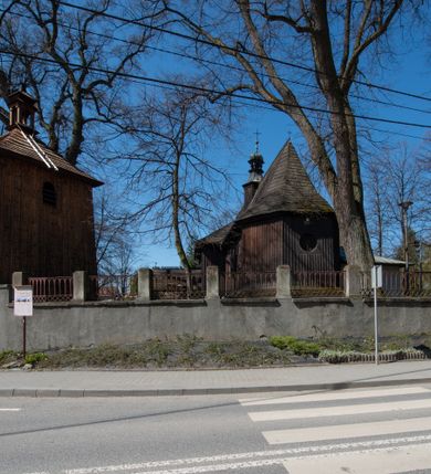 Zdjęcie nr 19: Kościół orientowany, pierwotnie na rzucie krzyża łacińskiego, jednonawowy, z kaplicami bocznymi od północy i południa, z prezbiterium prostokątnym zamkniętym wielobocznie. Obecnie w miejscu drewnianej kaplicy północnej murowana kaplica grobowa, a przy prezbiterium murowana prostokątna zakrystia i skarbczyk (1622 r.); nawa przedłużona ku zachodowi (1878-1879). Przy zachodniej części nawy, od południa, prostokątna drewniana kruchta. Wewnątrz stropy, w kaplicy północnej sklepienie krzyżowe z lunetami, w zakrystii i skarbczyku kolebkowe z lunetami. Zewnątrz zaszalowany. Dach nad nawą i prezbiterium jednokalenicowy, dwuspadowy o załamanych połaciach. Na kalenicy baniasta wieżyczka na sygnaturkę. Odrzwia zachodnie z nadprożem ozdobionym trójliściem z łukiem w ośli grzbiet oraz fryzem arkadkowym; odrzwia z prezbiterium do zakrystii z nadprożem ozdobionym łukiem w ośli grzbiet.