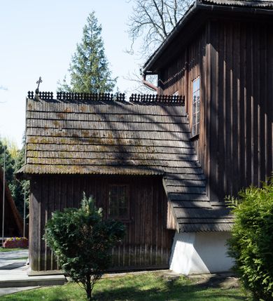 Zdjęcie nr 14: Kościół orientowany, pierwotnie na rzucie krzyża łacińskiego, jednonawowy, z kaplicami bocznymi od północy i południa, z prezbiterium prostokątnym zamkniętym wielobocznie. Obecnie w miejscu drewnianej kaplicy północnej murowana kaplica grobowa, a przy prezbiterium murowana prostokątna zakrystia i skarbczyk (1622 r.); nawa przedłużona ku zachodowi (1878-1879). Przy zachodniej części nawy, od południa, prostokątna drewniana kruchta. Wewnątrz stropy, w kaplicy północnej sklepienie krzyżowe z lunetami, w zakrystii i skarbczyku kolebkowe z lunetami. Zewnątrz zaszalowany. Dach nad nawą i prezbiterium jednokalenicowy, dwuspadowy o załamanych połaciach. Na kalenicy baniasta wieżyczka na sygnaturkę. Odrzwia zachodnie z nadprożem ozdobionym trójliściem z łukiem w ośli grzbiet oraz fryzem arkadkowym; odrzwia z prezbiterium do zakrystii z nadprożem ozdobionym łukiem w ośli grzbiet.