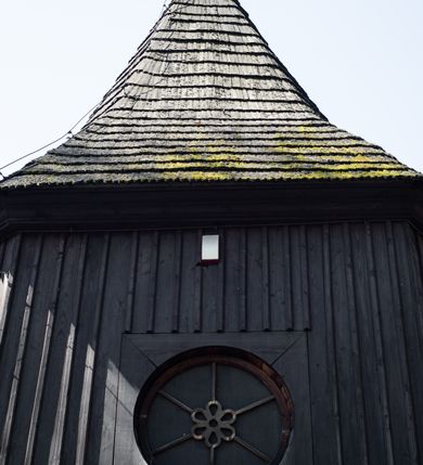 Zdjęcie nr 52: Kościół orientowany, pierwotnie na rzucie krzyża łacińskiego, jednonawowy, z kaplicami bocznymi od północy i południa, z prezbiterium prostokątnym zamkniętym wielobocznie. Obecnie w miejscu drewnianej kaplicy północnej murowana kaplica grobowa, a przy prezbiterium murowana prostokątna zakrystia i skarbczyk (1622 r.); nawa przedłużona ku zachodowi (1878-1879). Przy zachodniej części nawy, od południa, prostokątna drewniana kruchta. Wewnątrz stropy, w kaplicy północnej sklepienie krzyżowe z lunetami, w zakrystii i skarbczyku kolebkowe z lunetami. Zewnątrz zaszalowany. Dach nad nawą i prezbiterium jednokalenicowy, dwuspadowy o załamanych połaciach. Na kalenicy baniasta wieżyczka na sygnaturkę. Odrzwia zachodnie z nadprożem ozdobionym trójliściem z łukiem w ośli grzbiet oraz fryzem arkadkowym; odrzwia z prezbiterium do zakrystii z nadprożem ozdobionym łukiem w ośli grzbiet.