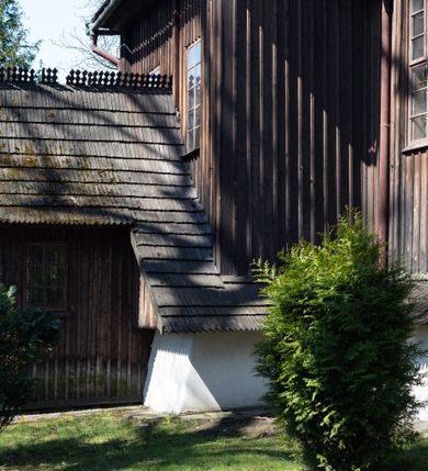 Zdjęcie nr 15: Kościół orientowany, pierwotnie na rzucie krzyża łacińskiego, jednonawowy, z kaplicami bocznymi od północy i południa, z prezbiterium prostokątnym zamkniętym wielobocznie. Obecnie w miejscu drewnianej kaplicy północnej murowana kaplica grobowa, a przy prezbiterium murowana prostokątna zakrystia i skarbczyk (1622 r.); nawa przedłużona ku zachodowi (1878-1879). Przy zachodniej części nawy, od południa, prostokątna drewniana kruchta. Wewnątrz stropy, w kaplicy północnej sklepienie krzyżowe z lunetami, w zakrystii i skarbczyku kolebkowe z lunetami. Zewnątrz zaszalowany. Dach nad nawą i prezbiterium jednokalenicowy, dwuspadowy o załamanych połaciach. Na kalenicy baniasta wieżyczka na sygnaturkę. Odrzwia zachodnie z nadprożem ozdobionym trójliściem z łukiem w ośli grzbiet oraz fryzem arkadkowym; odrzwia z prezbiterium do zakrystii z nadprożem ozdobionym łukiem w ośli grzbiet.