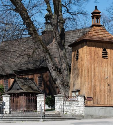 Zdjęcie nr 1: Kościół orientowany, pierwotnie na rzucie krzyża łacińskiego, jednonawowy, z kaplicami bocznymi od północy i południa, z prezbiterium prostokątnym zamkniętym wielobocznie. Obecnie w miejscu drewnianej kaplicy północnej murowana kaplica grobowa, a przy prezbiterium murowana prostokątna zakrystia i skarbczyk (1622 r.); nawa przedłużona ku zachodowi (1878-1879). Przy zachodniej części nawy, od południa, prostokątna drewniana kruchta. Wewnątrz stropy, w kaplicy północnej sklepienie krzyżowe z lunetami, w zakrystii i skarbczyku kolebkowe z lunetami. Zewnątrz zaszalowany. Dach nad nawą i prezbiterium jednokalenicowy, dwuspadowy o załamanych połaciach. Na kalenicy baniasta wieżyczka na sygnaturkę. Odrzwia zachodnie z nadprożem ozdobionym trójliściem z łukiem w ośli grzbiet oraz fryzem arkadkowym; odrzwia z prezbiterium do zakrystii z nadprożem ozdobionym łukiem w ośli grzbiet.