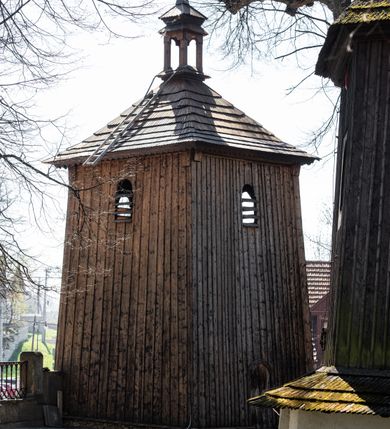 Zdjęcie nr 9: Kościół orientowany, pierwotnie na rzucie krzyża łacińskiego, jednonawowy, z kaplicami bocznymi od północy i południa, z prezbiterium prostokątnym zamkniętym wielobocznie. Obecnie w miejscu drewnianej kaplicy północnej murowana kaplica grobowa, a przy prezbiterium murowana prostokątna zakrystia i skarbczyk (1622 r.); nawa przedłużona ku zachodowi (1878-1879). Przy zachodniej części nawy, od południa, prostokątna drewniana kruchta. Wewnątrz stropy, w kaplicy północnej sklepienie krzyżowe z lunetami, w zakrystii i skarbczyku kolebkowe z lunetami. Zewnątrz zaszalowany. Dach nad nawą i prezbiterium jednokalenicowy, dwuspadowy o załamanych połaciach. Na kalenicy baniasta wieżyczka na sygnaturkę. Odrzwia zachodnie z nadprożem ozdobionym trójliściem z łukiem w ośli grzbiet oraz fryzem arkadkowym; odrzwia z prezbiterium do zakrystii z nadprożem ozdobionym łukiem w ośli grzbiet.