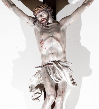 Zdjęcie nr 1: Chrystus rozpięty na krzyżu w silnym zwisie ciała, z szeroko rozłożonymi rękami, z głową opuszczoną na prawy bark, z nogami ugiętymi w kolanach; stopy założone lewa na prawą i przybite jednym gwoździem. Ciało esowato wygięte, muskularne, z podkreśloną budową anatomiczną. W prawym boku rana. Twarz trójkątna, z wydatnym nosem i kośćmi policzkowymi, okolona krótką brodą i włosami spływającymi na plecy, odsłaniającymi szyję i lewy bark, z kosmykiem włosów na prawym barku. Na włosy nałożona korona cierniowa upleciona z trzech grubych gałązek. Wokół bioder sznur podtrzymujący perizonium, które nie osłania prawego biodra, z końcem zwisającym wzdłuż prawego uda. Na górnej belce krzyża ułożony pionowo titulus o kształcie lekko pofałdowanej wstęgi z końcem wyciętym w jaskółczy ogon, z literami : J. N. / R. J. Karnacja ciała w jasnym odcieniu, z czerwonymi plamami krwi, włosy i broda brązowe, perizonium i titulus białe, krzyż w kolorze naturalnego drewna.