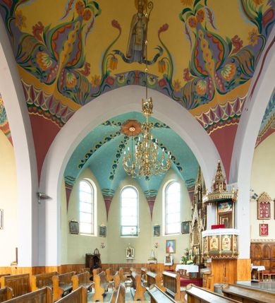 Zdjęcie nr 9: Kościół na planie krzyża łacińskiego, jednonawowy, z transeptem, zamknięty trójbocznym prezbiterium od północy i dobudowaną do niego zakrystią; na skrzyżowaniu nawy głównej i ramion transeptu wieżyczka na sygnaturkę. Fasadę tworzy masywna wieża, zwieńczona hełmem pokrytym blachą miedzianą. Główne wejście do kościoła od strony południowej, poprzez neoromański portal; wejścia boczne zlokalizowane od wschodu i zachodu, na styku nawy głównej i transeptu poprzez niewielkie kruchty. W oknach, w nawie współczesne witraże przedstawiające tajemnice różańca świętego; w prezbiterium Chrystusa ukrzyżowanego, św. Jana Pawła II i kardynała Stefana Wyszyńskiego, a w transepcie świętych zakonników: M. M. Alacoque, brata Alberta i siostrę Faustynę oraz św. Maksymiliana Marię Kolbego i bł. księdza Jerzego Popiełuszkę.
