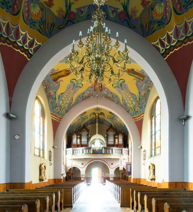 Zdjęcie nr 10: Kościół na planie krzyża łacińskiego, jednonawowy, z transeptem, zamknięty trójbocznym prezbiterium od północy i dobudowaną do niego zakrystią; na skrzyżowaniu nawy głównej i ramion transeptu wieżyczka na sygnaturkę. Fasadę tworzy masywna wieża, zwieńczona hełmem pokrytym blachą miedzianą. Główne wejście do kościoła od strony południowej, poprzez neoromański portal; wejścia boczne zlokalizowane od wschodu i zachodu, na styku nawy głównej i transeptu poprzez niewielkie kruchty. W oknach, w nawie współczesne witraże przedstawiające tajemnice różańca świętego; w prezbiterium Chrystusa ukrzyżowanego, św. Jana Pawła II i kardynała Stefana Wyszyńskiego, a w transepcie świętych zakonników: M. M. Alacoque, brata Alberta i siostrę Faustynę oraz św. Maksymiliana Marię Kolbego i bł. księdza Jerzego Popiełuszkę.
