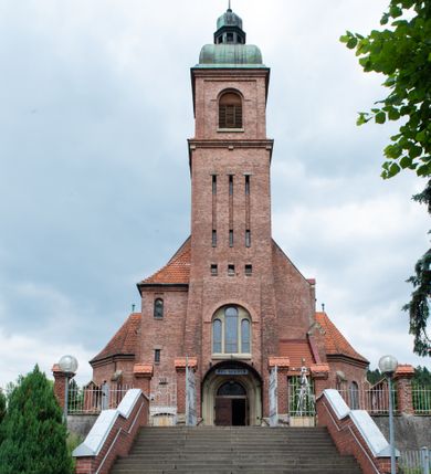 Zdjęcie nr 21: Kościół na planie krzyża łacińskiego, jednonawowy, z transeptem, zamknięty trójbocznym prezbiterium od północy i dobudowaną do niego zakrystią; na skrzyżowaniu nawy głównej i ramion transeptu wieżyczka na sygnaturkę. Fasadę tworzy masywna wieża, zwieńczona hełmem pokrytym blachą miedzianą. Główne wejście do kościoła od strony południowej, poprzez neoromański portal; wejścia boczne zlokalizowane od wschodu i zachodu, na styku nawy głównej i transeptu poprzez niewielkie kruchty. W oknach, w nawie współczesne witraże przedstawiające tajemnice różańca świętego; w prezbiterium Chrystusa ukrzyżowanego, św. Jana Pawła II i kardynała Stefana Wyszyńskiego, a w transepcie świętych zakonników: M. M. Alacoque, brata Alberta i siostrę Faustynę oraz św. Maksymiliana Marię Kolbego i bł. księdza Jerzego Popiełuszkę.
