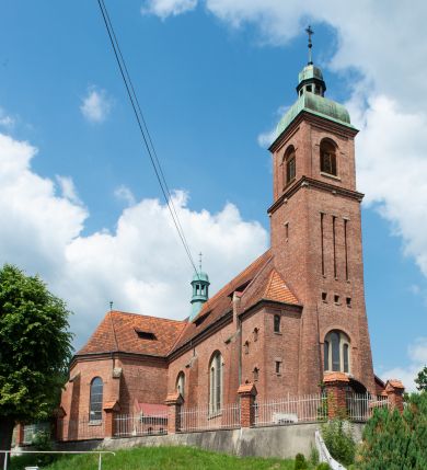 Zdjęcie nr 1: Kościół na planie krzyża łacińskiego, jednonawowy, z transeptem, zamknięty trójbocznym prezbiterium od północy i dobudowaną do niego zakrystią; na skrzyżowaniu nawy głównej i ramion transeptu wieżyczka na sygnaturkę. Fasadę tworzy masywna wieża, zwieńczona hełmem pokrytym blachą miedzianą. Główne wejście do kościoła od strony południowej, poprzez neoromański portal; wejścia boczne zlokalizowane od wschodu i zachodu, na styku nawy głównej i transeptu poprzez niewielkie kruchty. W oknach, w nawie współczesne witraże przedstawiające tajemnice różańca świętego; w prezbiterium Chrystusa ukrzyżowanego, św. Jana Pawła II i kardynała Stefana Wyszyńskiego, a w transepcie świętych zakonników: M. M. Alacoque, brata Alberta i siostrę Faustynę oraz św. Maksymiliana Marię Kolbego i bł. księdza Jerzego Popiełuszkę.

