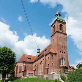 Zdjęcie nr 1: Kościół na planie krzyża łacińskiego, jednonawowy, z transeptem, zamknięty trójbocznym prezbiterium od północy i dobudowaną do niego zakrystią; na skrzyżowaniu nawy głównej i ramion transeptu wieżyczka na sygnaturkę. Fasadę tworzy masywna wieża, zwieńczona hełmem pokrytym blachą miedzianą. Główne wejście do kościoła od strony południowej, poprzez neoromański portal; wejścia boczne zlokalizowane od wschodu i zachodu, na styku nawy głównej i transeptu poprzez niewielkie kruchty. W oknach, w nawie współczesne witraże przedstawiające tajemnice różańca świętego; w prezbiterium Chrystusa ukrzyżowanego, św. Jana Pawła II i kardynała Stefana Wyszyńskiego, a w transepcie świętych zakonników: M. M. Alacoque, brata Alberta i siostrę Faustynę oraz św. Maksymiliana Marię Kolbego i bł. księdza Jerzego Popiełuszkę.
