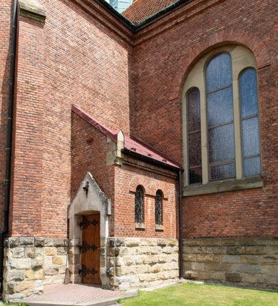 Zdjęcie nr 24: Kościół na planie krzyża łacińskiego, jednonawowy, z transeptem, zamknięty trójbocznym prezbiterium od północy i dobudowaną do niego zakrystią; na skrzyżowaniu nawy głównej i ramion transeptu wieżyczka na sygnaturkę. Fasadę tworzy masywna wieża, zwieńczona hełmem pokrytym blachą miedzianą. Główne wejście do kościoła od strony południowej, poprzez neoromański portal; wejścia boczne zlokalizowane od wschodu i zachodu, na styku nawy głównej i transeptu poprzez niewielkie kruchty. W oknach, w nawie współczesne witraże przedstawiające tajemnice różańca świętego; w prezbiterium Chrystusa ukrzyżowanego, św. Jana Pawła II i kardynała Stefana Wyszyńskiego, a w transepcie świętych zakonników: M. M. Alacoque, brata Alberta i siostrę Faustynę oraz św. Maksymiliana Marię Kolbego i bł. księdza Jerzego Popiełuszkę.
