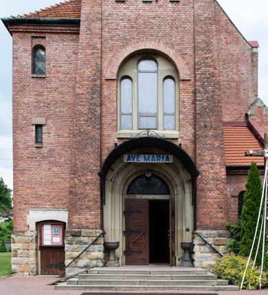 Zdjęcie nr 22: Kościół na planie krzyża łacińskiego, jednonawowy, z transeptem, zamknięty trójbocznym prezbiterium od północy i dobudowaną do niego zakrystią; na skrzyżowaniu nawy głównej i ramion transeptu wieżyczka na sygnaturkę. Fasadę tworzy masywna wieża, zwieńczona hełmem pokrytym blachą miedzianą. Główne wejście do kościoła od strony południowej, poprzez neoromański portal; wejścia boczne zlokalizowane od wschodu i zachodu, na styku nawy głównej i transeptu poprzez niewielkie kruchty. W oknach, w nawie współczesne witraże przedstawiające tajemnice różańca świętego; w prezbiterium Chrystusa ukrzyżowanego, św. Jana Pawła II i kardynała Stefana Wyszyńskiego, a w transepcie świętych zakonników: M. M. Alacoque, brata Alberta i siostrę Faustynę oraz św. Maksymiliana Marię Kolbego i bł. księdza Jerzego Popiełuszkę.
