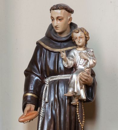 Zdjęcie nr 1: Feretron z pełnoplastyczną rzeźbą św. Antoniego Padewskiego z Dzieciątkiem, umieszczoną na prostopadłościennej podstawie. Podstawa na planie kwadratu, zaopatrzona w otwory na drążki do noszenia, wsparta na czterech nóżkach, na niej kilkustopniowy cokół o ściętych narożach. Święty ustawiony frontalnie, w delikatnym kontrapoście, z prawą nogą ugiętą w kolanie, z Dzieciątkiem Jezus na lewym ręku, z małym bochenkiem chleba w prawej, z głową skierowaną w prawo. Twarz okrągła, młodzieńcza, o delikatnych rysach, na głowie tonsura. Ubrany w habit franciszkański, przewiązany sznurem, z różańcem u boku. Dzieciątko zwrócone frontalnie, ukazane w pozycji siedzącej, z lewą ręką złożoną na piersi, prawą czyniące gest błogosławieństwa. Ubrane w sukienkę z długimi rękawami. Polichromia naturalistyczna, szata Dzieciątka i sznur srebrzone, detale złocone.
