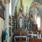 Zdjęcie nr 1: Neogotycki, przyścienny, jednokondygnacyjny ołtarz Matki Boskiej Różańcowej uzyskał architektoniczną strukturę ze zwieńczeniem. Kolorystyka ołtarza utrzymana została w tonacji ciemnego, bejcowanego drewna. Detale, ornamenty zostały wyzłocone, natomiast wypełnienia maswerków i ram wimperg są białe. Z kolei pole ramy głównego obrazu wykonano jako czerwone. Retabulum ustawiono na podwójnych gradusach zaokrąglonych od przodu. Stipes ołtarzowy uzyskał kształt prostopadłościanu z trzema czworobocznymi płycinami od frontu, ujętymi złoconymi i profilowanymi obramieniami. Płyciny rozdzielają  półkolumienki na wysokich cokolikach. Dwie skrajne płyciny stipesu wypełniono u góry maswerkiem, natomiast w środkowej znalazł się równoramienny krzyż wpisany w czteroliść. Stipes podtrzymuje drewnianą mensę z portatylem. Ołtarz przylega do wysokiego, prostopadłościennego cokołu flankowanego po bokach kolumienkami, na którym wspiera się cała nastawa. Widoczne jego partie zdobią prostokątne płyciny w obramieniach. Na cokole wspiera się predella podzielona płytkimi, prostokątnymi płycinami zakończonymi ostrołukowymi arkadkami z noskami, wypełnionymi płaskorzeźbionym i złoconym ornamentem roślinnym. Pośrodku, w przerwie między płycinami predelli, usytuowano prostopadłościenne tabernakulum w formie kapliczki, zwieńczone łukiem siodłowym, flankowane dwoma pinaklami. Ostrołukowe drzwiczki tabernakulum zdobi skrzyżowana z krzyżem kotwica oraz wyobrażenie Boskiego Serca Pana Jezusa. Poniżej widoczna jest girlanda różana. Predella wspiera trójosiową kondygnację ze zwieńczeniem. Na osi środkowej usytuowano płytką, prostokątną wnękę zakończoną ostrołukiem z arkaturą. Flankują ją smukłe kolumienki na wysokich cokolikach wspierające wysokie pinakle. Ponad wnęką widoczna jest wimperga z maswerkiem dekorowana czołgankami i kwiatonem. We wnęce umieszczono płaskorzeźbione i polichromowane przedstawienie Matki Boskiej Różańcowej ze św. Dominikiem i św. Katarzyną ze Sieny, a na zasuwie obraz ze św. Barbarą. W osiach skrajnych, pod gotyckimi baldachimami z wimpergami, rozdzielonymi pinaklami, ustawiono w niszach na postumentach figury św. Wojciecha i św. Stanisława. Święci zostali podpisani na postumentach. Konchy nisz są jasnoniebieskie natomiast ich ścianki zielone. Boki baldachimów udekorowano małymi wimpergami rozdzielonymi smukłymi pinaklami z kwiatonami i czołgankami. Baldachimy przechodzą w smukłe, ażurowe fiale dekorowane pinaklami i czołgankami oraz kwiatonami. Zwieńczenie nastawy na osi środkowej uzyskało kształt otwartej kapliczki z niszą zakończoną smukłą fialą z iglicą, dekorowaną czołgankami i kwiatonem. Po bokach kapliczki znajdują się ażurowe przypory wypełnione maswerkiem, flankowane pinaklami. W niszy umieszczono figurę św. Józefa z Dzieciątkiem. Całość retabulum flankują uszaki w formie ażurowych przypór, wypełnionych maswerkami i zdobionych parą pinakli.

