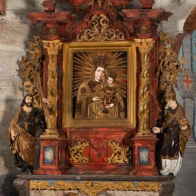 Zdjęcie nr 1: Nastawa ołtarzowa otrzymała formę jednokondygnacyjnej i jednoosiowej struktury architektonicznej wspartej na dwóch złoconych i kręconych kolumnach ze zwieńczeniem. Całość struktury pokryta jest marmoryzacją w kolorze palonej sieny. Drewniana mensa z portatylem o ściętych narożach wspiera się na prostopadłościennym stipesie ołtarzowym z fazowanym cokolikiem, ustawionym na stopniu. W miejscu ściętych naroży stipesu wprowadzono od frontu dwa srebrzone i złocone spływy wolutowe dodatkowo dekorowane motywem kampanuli. Przód stipesu zdobi jasna marmoryzacja oraz dwie poziome, płaskorzeźbione i złocone listwy z motywem ornamentu rocaille'owego umieszczone pod mensą i nad cokolikiem. W centrum retabulum znalazł się obraz Matki Boskiej z Dzieciątkiem w typie Piekarskim zdobiony drewnianą, złoconą sukienką wotywną. Ponad obrazem w profilowanych, złotych ramach umieszczono płaskorzeźbiony i złocony ornament z motywem suchego liścia akantowego, zamknięty fantazyjnym obramieniem. Obraz flankują dwie złocone, spiralne kolumny z korynckimi kapitelami o trzonach zdobionych wicią roślinno-kwiatową. Na wysokich postumentach, których boki zdobią płyciny ujęte w profilowane listwy, ustawiono kolumny. Pomiędzy postumentami pierwotnie znajdowało się niezachowane dziś tabernakulum, flankowane zachowaną po bokach ażurową, złoconą wicią roślinną. Kolumny podtrzymują wysokie imposty zdobione ornamentem roślinnym, na których wsparto wyłamane na środku i mocno wysunięte do przodu belkowanie. W części środkowej silnie artykułowane, wyłamane belkowanie podniesiono do góry wieńcząc go rzeźbionym owalem imitującym wieniec laurowy, wypełnionym malowanym przedstawieniem gołębicy Ducha Świętego. Otacza go ażurowa dekoracja utworzona ze złoconej, suchej wici akantowej oraz ustawiona na szczycie waza płomienista. Ponad belkowaniem na przedłużeniu kolumn, na wysokich cokołach, umieszczono figury aniołów z rozpostartymi skrzydłami, które w jednej ręce trzymają lance, a w drugiej kartusze herbowe. Anioł z lewej strony trzyma kartusz z godłem herbu Jastrzębiec, natomiast anioł z prawej kartusz z godłem herbu Kornicz. Po bokach kolumn ustawiono z lewej figurę św. Andrzeja Apostoła, a z prawej św. Mikołaja biskupa. Retabulum flankują dwa ażurowe, złocone uszaki utworzone ze stylizowanej suchej wici akantowej.