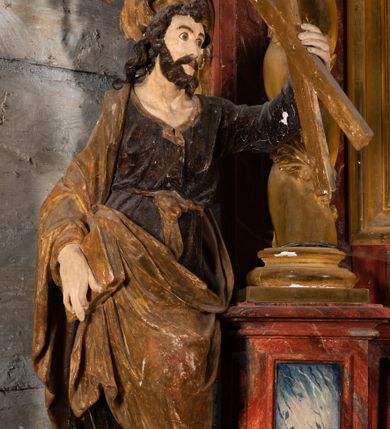 Zdjęcie nr 12: Nastawa ołtarzowa otrzymała formę jednokondygnacyjnej i jednoosiowej struktury architektonicznej wspartej na dwóch złoconych i kręconych kolumnach ze zwieńczeniem. Całość struktury pokryta jest marmoryzacją w kolorze palonej sieny. Drewniana mensa z portatylem o ściętych narożach wspiera się na prostopadłościennym stipesie ołtarzowym z fazowanym cokolikiem, ustawionym na stopniu. W miejscu ściętych naroży stipesu wprowadzono od frontu dwa srebrzone i złocone spływy wolutowe dodatkowo dekorowane motywem kampanuli. Przód stipesu zdobi jasna marmoryzacja oraz dwie poziome, płaskorzeźbione i złocone listwy z motywem ornamentu rocaille'owego umieszczone pod mensą i nad cokolikiem. W centrum retabulum znalazł się obraz Matki Boskiej z Dzieciątkiem w typie Piekarskim zdobiony drewnianą, złoconą sukienką wotywną. Ponad obrazem w profilowanych, złotych ramach umieszczono płaskorzeźbiony i złocony ornament z motywem suchego liścia akantowego, zamknięty fantazyjnym obramieniem. Obraz flankują dwie złocone, spiralne kolumny z korynckimi kapitelami o trzonach zdobionych wicią roślinno-kwiatową. Na wysokich postumentach, których boki zdobią płyciny ujęte w profilowane listwy, ustawiono kolumny. Pomiędzy postumentami pierwotnie znajdowało się niezachowane dziś tabernakulum, flankowane zachowaną po bokach ażurową, złoconą wicią roślinną. Kolumny podtrzymują wysokie imposty zdobione ornamentem roślinnym, na których wsparto wyłamane na środku i mocno wysunięte do przodu belkowanie. W części środkowej silnie artykułowane, wyłamane belkowanie podniesiono do góry wieńcząc go rzeźbionym owalem imitującym wieniec laurowy, wypełnionym malowanym przedstawieniem gołębicy Ducha Świętego. Otacza go ażurowa dekoracja utworzona ze złoconej, suchej wici akantowej oraz ustawiona na szczycie waza płomienista. Ponad belkowaniem na przedłużeniu kolumn, na wysokich cokołach, umieszczono figury aniołów z rozpostartymi skrzydłami, które w jednej ręce trzymają lance, a w drugiej kartusze herbowe. Anioł z lewej strony trzyma kartusz z godłem herbu Jastrzębiec, natomiast anioł z prawej kartusz z godłem herbu Kornicz. Po bokach kolumn ustawiono z lewej figurę św. Andrzeja Apostoła, a z prawej św. Mikołaja biskupa. Retabulum flankują dwa ażurowe, złocone uszaki utworzone ze stylizowanej suchej wici akantowej.