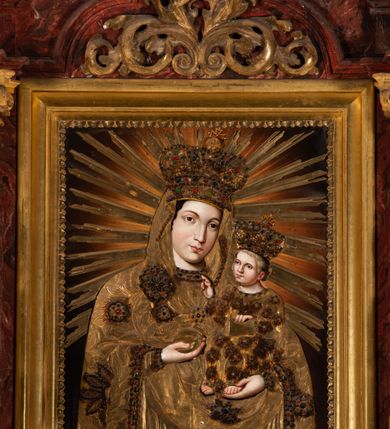 Zdjęcie nr 2: Nastawa ołtarzowa otrzymała formę jednokondygnacyjnej i jednoosiowej struktury architektonicznej wspartej na dwóch złoconych i kręconych kolumnach ze zwieńczeniem. Całość struktury pokryta jest marmoryzacją w kolorze palonej sieny. Drewniana mensa z portatylem o ściętych narożach wspiera się na prostopadłościennym stipesie ołtarzowym z fazowanym cokolikiem, ustawionym na stopniu. W miejscu ściętych naroży stipesu wprowadzono od frontu dwa srebrzone i złocone spływy wolutowe dodatkowo dekorowane motywem kampanuli. Przód stipesu zdobi jasna marmoryzacja oraz dwie poziome, płaskorzeźbione i złocone listwy z motywem ornamentu rocaille&#039;owego umieszczone pod mensą i nad cokolikiem. W centrum retabulum znalazł się obraz Matki Boskiej z Dzieciątkiem w typie Piekarskim zdobiony drewnianą, złoconą sukienką wotywną. Ponad obrazem w profilowanych, złotych ramach umieszczono płaskorzeźbiony i złocony ornament z motywem suchego liścia akantowego, zamknięty fantazyjnym obramieniem. Obraz flankują dwie złocone, spiralne kolumny z korynckimi kapitelami o trzonach zdobionych wicią roślinno-kwiatową. Na wysokich postumentach, których boki zdobią płyciny ujęte w profilowane listwy, ustawiono kolumny. Pomiędzy postumentami pierwotnie znajdowało się niezachowane dziś tabernakulum, flankowane zachowaną po bokach ażurową, złoconą wicią roślinną. Kolumny podtrzymują wysokie imposty zdobione ornamentem roślinnym, na których wsparto wyłamane na środku i mocno wysunięte do przodu belkowanie. W części środkowej silnie artykułowane, wyłamane belkowanie podniesiono do góry wieńcząc go rzeźbionym owalem imitującym wieniec laurowy, wypełnionym malowanym przedstawieniem gołębicy Ducha Świętego. Otacza go ażurowa dekoracja utworzona ze złoconej, suchej wici akantowej oraz ustawiona na szczycie waza płomienista. Ponad belkowaniem na przedłużeniu kolumn, na wysokich cokołach, umieszczono figury aniołów z rozpostartymi skrzydłami, które w jednej ręce trzymają lance, a w drugiej kartusze herbowe. Anioł z lewej strony trzyma kartusz z godłem herbu Jastrzębiec, natomiast anioł z prawej kartusz z godłem herbu Kornicz. Po bokach kolumn ustawiono z lewej figurę św. Andrzeja Apostoła, a z prawej św. Mikołaja biskupa. Retabulum flankują dwa ażurowe, złocone uszaki utworzone ze stylizowanej suchej wici akantowej.