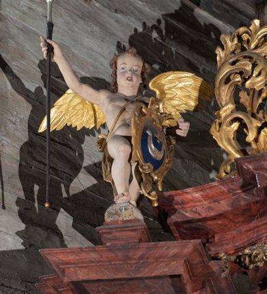 Zdjęcie nr 4: Nastawa ołtarzowa otrzymała formę jednokondygnacyjnej i jednoosiowej struktury architektonicznej wspartej na dwóch złoconych i kręconych kolumnach ze zwieńczeniem. Całość struktury pokryta jest marmoryzacją w kolorze palonej sieny. Drewniana mensa z portatylem o ściętych narożach wspiera się na prostopadłościennym stipesie ołtarzowym z fazowanym cokolikiem, ustawionym na stopniu. W miejscu ściętych naroży stipesu wprowadzono od frontu dwa srebrzone i złocone spływy wolutowe dodatkowo dekorowane motywem kampanuli. Przód stipesu zdobi jasna marmoryzacja oraz dwie poziome, płaskorzeźbione i złocone listwy z motywem ornamentu rocaille&#039;owego umieszczone pod mensą i nad cokolikiem. W centrum retabulum znalazł się obraz Matki Boskiej z Dzieciątkiem w typie Piekarskim zdobiony drewnianą, złoconą sukienką wotywną. Ponad obrazem w profilowanych, złotych ramach umieszczono płaskorzeźbiony i złocony ornament z motywem suchego liścia akantowego, zamknięty fantazyjnym obramieniem. Obraz flankują dwie złocone, spiralne kolumny z korynckimi kapitelami o trzonach zdobionych wicią roślinno-kwiatową. Na wysokich postumentach, których boki zdobią płyciny ujęte w profilowane listwy, ustawiono kolumny. Pomiędzy postumentami pierwotnie znajdowało się niezachowane dziś tabernakulum, flankowane zachowaną po bokach ażurową, złoconą wicią roślinną. Kolumny podtrzymują wysokie imposty zdobione ornamentem roślinnym, na których wsparto wyłamane na środku i mocno wysunięte do przodu belkowanie. W części środkowej silnie artykułowane, wyłamane belkowanie podniesiono do góry wieńcząc go rzeźbionym owalem imitującym wieniec laurowy, wypełnionym malowanym przedstawieniem gołębicy Ducha Świętego. Otacza go ażurowa dekoracja utworzona ze złoconej, suchej wici akantowej oraz ustawiona na szczycie waza płomienista. Ponad belkowaniem na przedłużeniu kolumn, na wysokich cokołach, umieszczono figury aniołów z rozpostartymi skrzydłami, które w jednej ręce trzymają lance, a w drugiej kartusze herbowe. Anioł z lewej strony trzyma kartusz z godłem herbu Jastrzębiec, natomiast anioł z prawej kartusz z godłem herbu Kornicz. Po bokach kolumn ustawiono z lewej figurę św. Andrzeja Apostoła, a z prawej św. Mikołaja biskupa. Retabulum flankują dwa ażurowe, złocone uszaki utworzone ze stylizowanej suchej wici akantowej.