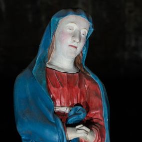 Zdjęcie nr 1: Figura ukazuje w całej postaci stojącą na płaskim postumencie w nieznacznym kontrapoście Matkę Boską. Maria została przedstawiona frontalnie z nieznacznie pochyloną głową w lewą stronę oraz boleśnie zaplecionymi dłońmi trzymanymi na wysokości pasa. Ma pociągłą twarz o jasnej karnacji, duży nos, wąskie usta i półprzymknięte oczy. Ubrana jest w niebieski maforion, spod którego widać brązowe włosy spływające na ramiona oraz czerwoną suknię przewiązaną w talii białą szarfą. Prawa poła maforionu podwinięta jest pod prawą rękę. Spod sukni widoczne są jej bose stopy.