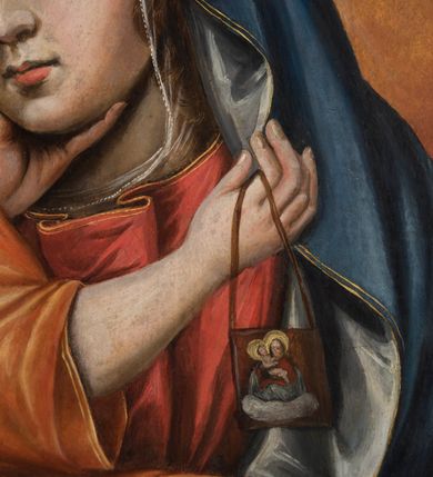 Zdjęcie nr 9: Dwustronnie malowany obraz ma kształt stojącego prostokąta zbliżonego do kwadratu. Ujmuje go szeroka, płaska rama, zdobiona grawerowanym pasem ornamentalnym składającym się z liści i kwiatów. Ornament zamykają złocone profile ramy. Na awersie obrazu wyobrażono Matkę Boską Szkaplerzną, a na rewersie Matkę Boską Bolesną w typie Piety. Matka Boska Szkaplerzna została przedstawiona frontalnie w półpostaci z lekko pochyloną głową w prawo i twarzą widoczną w trzech czwartych. Ubrana jest w czerwoną suknię okrytą niebieskim maforionem lamowanym złotą tasiemką. Spod niego uwidacznia się przeźroczysty welon osłaniający włosy. Jej twarz charakteryzuje łagodne spojrzenie skierowanych w dal, przed siebie, dużych, brązowych oczu. Maria ma jasną karnację, długi prosty nos i wąskie usta o lekko wydatnej dolnej wardze. W lewej dłoni Maryja ma szkaplerz. Do jej policzka tuli się Dzieciątko trzymane obiema rękami na prawym przedramieniu. Jezus lewą ręką chwyta się za podbródek Matki, także trzymając w prawej lekko zgiętej ręce szkaplerz. Dzieciątko ma pociągłą twarz otoczoną kręconymi, krótkimi, jasnymi włosami. Charakteryzuje ją wysokie czoło, rumiane policzki oraz mały nos i wąskie usta. Mały Jezus ubrany jest w złocisto-cynobrową tunikę odsłaniającą jego prawą rękę oraz prawą nóżkę przełożoną przez rękę Matki. Oba szkaplerze na obrazie zdobi niewielkie przedstawienie w półpostaci Matki Boskiej z Dzieciątkiem na obłoku. Trzymany przez Maryję szkaplerz przechodzi przez półkolisty łuk o architektonicznej strukturze widniejący pod postaciami w dolnej części obrazu. Pod nim przedstawiono dusze czyśćcowe w ognistych płomieniach. Postać Madonny i Dzieciątka otaczają świetliste nimby kontrastujące z złocisto-cynobrowym tłem obrazu. Na ich głowach przytwierdzone są w formie aplikacji srebrne, ażurowe i kameryzowane korony zamknięte, utworzone z ornamentu małżowinowo-chrząstkowego oraz akantowego, zwieńczone kulami z krzyżami równoramiennymi.