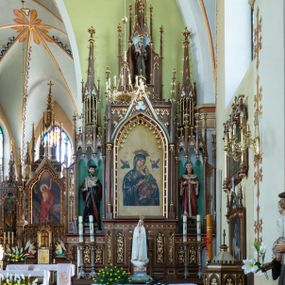 Zdjęcie nr 1: Neogotycki, przyścienny, jednokondygnacyjny ołtarz Świętej Rodziny uzyskał architektoniczną strukturę ze zwieńczeniem. Kolorystyka ołtarza utrzymana została w tonacji ciemnego, bejcowanego drewna. Detale, ornamenty zostały wyzłocone, natomiast wypełnienia maswerków i ram wimperg są białe. Z kolei pole ramy głównego obrazu wykonano jako czerwone. Retabulum ustawiono na podwójnych gradusach zaokrąglonych od przodu. Stipes ołtarzowy uzyskał kształt prostopadłościanu z trzema czworobocznymi płycinami od frontu, ujętymi złoconymi i profilowanymi obramieniami. Płyciny rozdzielają półkolumienki na wysokich cokolikach. Dwie skrajne płyciny stipesu wypełniono u góry maswerkiem, natomiast w środkowej znalazł się równoramienny krzyż wpisany w czteroliść. Stipes podtrzymuje drewnianą mensę z portatylem. Ołtarz przylega do wysokiego, prostopadłościennego cokołu flankowanego po bokach kolumienkami, na którym wspiera się cała nastawa. Widoczne jego partie zdobią prostokątne płyciny w obramieniach. Na cokole wspiera się predella podzielona płytkimi, prostokątnymi płycinami zakończonymi ostrołukowymi arkadkami z noskami, wypełnionymi płaskorzeźbionym i złoconym ornamentem roślinnym. Pośrodku, w przerwie między płycinami predelli, usytuowano prostopadłościenne tabernakulum w formie kapliczki, zwieńczone łukiem siodłowym, flankowane dwoma pinaklami. Ostrołukowe drzwiczki tabernakulum zdobi skrzyżowana z krzyżem kotwica oraz wyobrażenie Boskiego Serca Pana Jezusa. Poniżej widoczna jest girlanda różana. Nad drzwiczkami umieszczono stylizowany ornament roślinny. Predella wspiera trójosiową kondygnację ze zwieńczeniem. Na osi środkowej usytuowano płytką, prostokątną wnękę zakończoną ostrołukiem z arkaturą. Flankują ją smukłe kolumienki na wysokich cokolikach wspierające wysokie pinakle. Ponad wnęką widoczna jest wimperga z maswerkiem dekorowana czołgankami i kwiatonem. We wnęce umieszczono pełnoplastyczne rzeźby Matki Boskiej i św. Józefa, pomiędzy którymi stoi mały Jezus, a na zasuwie obraz Matki Boskiej Nieustającej Pomocy. W osiach skrajnych, pod gotyckimi baldachimami z wimpergami, rozdzielonymi pinaklami, ustawiono w niszach na postumentach figury św. Jana Kantego i św. Kazimierza Królewicza. Święci są podpisani na postumentach. Konchy nisz są jasnoniebieskie natomiast ich ścianki zielone. Boki baldachimów udekorowano małymi wimpergami rozdzielonymi smukłymi pinaklami z kwiatonami i czołgankami. Baldachimy przechodzą w smukłe, ażurowe fiale dekorowane pinaklami i czołgankami oraz kwiatonami. Zwieńczenie nastawy na osi środkowej uzyskało kształt otwartej kapliczki z niszą zakończoną smukłą fialą z iglicą, dekorowaną czołgankami i kwiatonem. Po bokach kapliczki znajdują się przypory dekorowane maswerkiem i flankowane pinaklami. W niszy umieszczono figurę św. Antoniego z Padwy, którego podpisano na postumencie. Całość retabulum flankują uszaki w formie ażurowych przypór, wypełnionych maswerkami i zdobionych parą pinakli.
