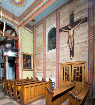 Zdjęcie nr 8: Kościół, otoczony starodrzewiem, położony jest na niewielkim wzniesieniu ponad stawami w centrum wsi. Jest to budowla drewniano-murowana, orientowana. Nawa została wzniesiona w 1518 roku na zrąb na rzucie zbliżonym do kwadratu, nakryta płaskim stropem. Od zachodu do nawy przylega wzniesiona w tym samym roku wieża o konstrukcji słupowej, pierwotnie kwadratowa o pochyłych ścianach, w 1782 roku poszerzona przez obudowanie drugą konstrukcją, prawie pionową. Wieża, w całości szalowana, poprzedzona niewielką kruchtą, w połowie wysokości jest opasana daszkiem pulpitowym. Jej hełm posiada kształt kopuły zwieńczonej ostrosłupem. Od południa do nawy przylega drewniana kruchta z 1924 roku, a od wschodu murowane prezbiterium z 1931 roku. Prezbiterium otwiera się podwójnymi arkadami na dwie kaplice boczne - wzniesioną od południa w 1861 roku z kryptą grobową Duninów oraz kaplicę przylegającą od północy zbudowaną w 1931 roku. Jego przestrzeń nakryto sklepieniem kolebkowym na gurtach, zaś dwuprzęsłowe kaplice sklepieniem krzyżowym. Za prezbiterium wznosi się murowana, piętrowa zakrystia z XVII wieku przykryta sklepieniem nieckowym z lunetami i małym zwierciadłem, zdobionym monogramem maryjnym. Jednokalenicowy dach nawy i prezbiterium pokryty jest dachówką. Nad końcu dachu nawy od wschodu nadwieszono wieżyczkę na sygnaturkę z latarnią i cebulastą banią, zwieńczoną krzyżem. Zakrystia nakryta została namiotowym dachem polskim, także pokrytym dachówką. Na zewnętrznych ścianach części murowanej umieszczono kilka epitafiów przeniesionych z wnętrza kościoła. Wewnątrz prezbiterium na ścianie wschodniej, nad wejściem do zakrystii, zawieszono manierystyczny, dwukondygnacyjny ołtarz główny z XVII wieku z uszakami zdobionymi herbami Starykoń i Jelita. Przy ścianie północnej, w miejscu połączenia nawy drewnianej z murowanym prezbiterium, usytuowano w 1931 roku ambonę oraz kamienną chrzcielnicę z 1658 roku. Belkę tęczową zdobi osiemnastowieczna grupa Ukrzyżowania. W kaplicach bocznych ustawiono dwa neobarokowe ołtarze boczne.  