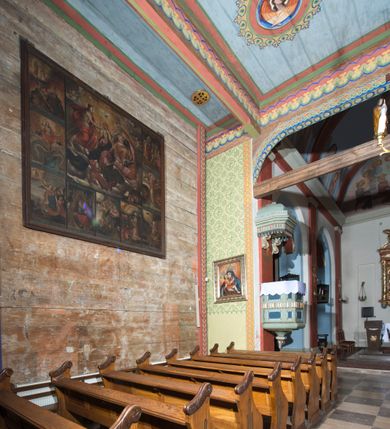 Zdjęcie nr 7: Kościół, otoczony starodrzewiem, położony jest na niewielkim wzniesieniu ponad stawami w centrum wsi. Jest to budowla drewniano-murowana, orientowana. Nawa została wzniesiona w 1518 roku na zrąb na rzucie zbliżonym do kwadratu, nakryta płaskim stropem. Od zachodu do nawy przylega wzniesiona w tym samym roku wieża o konstrukcji słupowej, pierwotnie kwadratowa o pochyłych ścianach, w 1782 roku poszerzona przez obudowanie drugą konstrukcją, prawie pionową. Wieża, w całości szalowana, poprzedzona niewielką kruchtą, w połowie wysokości jest opasana daszkiem pulpitowym. Jej hełm posiada kształt kopuły zwieńczonej ostrosłupem. Od południa do nawy przylega drewniana kruchta z 1924 roku, a od wschodu murowane prezbiterium z 1931 roku. Prezbiterium otwiera się podwójnymi arkadami na dwie kaplice boczne - wzniesioną od południa w 1861 roku z kryptą grobową Duninów oraz kaplicę przylegającą od północy zbudowaną w 1931 roku. Jego przestrzeń nakryto sklepieniem kolebkowym na gurtach, zaś dwuprzęsłowe kaplice sklepieniem krzyżowym. Za prezbiterium wznosi się murowana, piętrowa zakrystia z XVII wieku przykryta sklepieniem nieckowym z lunetami i małym zwierciadłem, zdobionym monogramem maryjnym. Jednokalenicowy dach nawy i prezbiterium pokryty jest dachówką. Nad końcu dachu nawy od wschodu nadwieszono wieżyczkę na sygnaturkę z latarnią i cebulastą banią, zwieńczoną krzyżem. Zakrystia nakryta została namiotowym dachem polskim, także pokrytym dachówką. Na zewnętrznych ścianach części murowanej umieszczono kilka epitafiów przeniesionych z wnętrza kościoła. Wewnątrz prezbiterium na ścianie wschodniej, nad wejściem do zakrystii, zawieszono manierystyczny, dwukondygnacyjny ołtarz główny z XVII wieku z uszakami zdobionymi herbami Starykoń i Jelita. Przy ścianie północnej, w miejscu połączenia nawy drewnianej z murowanym prezbiterium, usytuowano w 1931 roku ambonę oraz kamienną chrzcielnicę z 1658 roku. Belkę tęczową zdobi osiemnastowieczna grupa Ukrzyżowania. W kaplicach bocznych ustawiono dwa neobarokowe ołtarze boczne.  