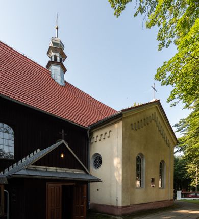 Zdjęcie nr 20: Kościół, otoczony starodrzewiem, położony jest na niewielkim wzniesieniu ponad stawami w centrum wsi. Jest to budowla drewniano-murowana, orientowana. Nawa została wzniesiona w 1518 roku na zrąb na rzucie zbliżonym do kwadratu, nakryta płaskim stropem. Od zachodu do nawy przylega wzniesiona w tym samym roku wieża o konstrukcji słupowej, pierwotnie kwadratowa o pochyłych ścianach, w 1782 roku poszerzona przez obudowanie drugą konstrukcją, prawie pionową. Wieża, w całości szalowana, poprzedzona niewielką kruchtą, w połowie wysokości jest opasana daszkiem pulpitowym. Jej hełm posiada kształt kopuły zwieńczonej ostrosłupem. Od południa do nawy przylega drewniana kruchta z 1924 roku, a od wschodu murowane prezbiterium z 1931 roku. Prezbiterium otwiera się podwójnymi arkadami na dwie kaplice boczne - wzniesioną od południa w 1861 roku z kryptą grobową Duninów oraz kaplicę przylegającą od północy zbudowaną w 1931 roku. Jego przestrzeń nakryto sklepieniem kolebkowym na gurtach, zaś dwuprzęsłowe kaplice sklepieniem krzyżowym. Za prezbiterium wznosi się murowana, piętrowa zakrystia z XVII wieku przykryta sklepieniem nieckowym z lunetami i małym zwierciadłem, zdobionym monogramem maryjnym. Jednokalenicowy dach nawy i prezbiterium pokryty jest dachówką. Nad końcu dachu nawy od wschodu nadwieszono wieżyczkę na sygnaturkę z latarnią i cebulastą banią, zwieńczoną krzyżem. Zakrystia nakryta została namiotowym dachem polskim, także pokrytym dachówką. Na zewnętrznych ścianach części murowanej umieszczono kilka epitafiów przeniesionych z wnętrza kościoła. Wewnątrz prezbiterium na ścianie wschodniej, nad wejściem do zakrystii, zawieszono manierystyczny, dwukondygnacyjny ołtarz główny z XVII wieku z uszakami zdobionymi herbami Starykoń i Jelita. Przy ścianie północnej, w miejscu połączenia nawy drewnianej z murowanym prezbiterium, usytuowano w 1931 roku ambonę oraz kamienną chrzcielnicę z 1658 roku. Belkę tęczową zdobi osiemnastowieczna grupa Ukrzyżowania. W kaplicach bocznych ustawiono dwa neobarokowe ołtarze boczne.  