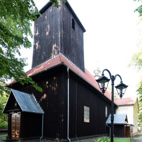 Zdjęcie nr 1: Kościół, otoczony starodrzewiem, położony jest na niewielkim wzniesieniu ponad stawami w centrum wsi. Jest to budowla drewniano-murowana, orientowana. Nawa została wzniesiona w 1518 roku na zrąb na rzucie zbliżonym do kwadratu, nakryta płaskim stropem. Od zachodu do nawy przylega wzniesiona w tym samym roku wieża o konstrukcji słupowej, pierwotnie kwadratowa o pochyłych ścianach, w 1782 roku poszerzona przez obudowanie drugą konstrukcją, prawie pionową. Wieża, w całości szalowana, poprzedzona niewielką kruchtą, w połowie wysokości jest opasana daszkiem pulpitowym. Jej hełm posiada kształt kopuły zwieńczonej ostrosłupem. Od południa do nawy przylega drewniana kruchta z 1924 roku, a od wschodu murowane prezbiterium z 1931 roku. Prezbiterium otwiera się podwójnymi arkadami na dwie kaplice boczne - wzniesioną od południa w 1861 roku z kryptą grobową Duninów oraz kaplicę przylegającą od północy zbudowaną w 1931 roku. Jego przestrzeń nakryto sklepieniem kolebkowym na gurtach, zaś dwuprzęsłowe kaplice sklepieniem krzyżowym. Za prezbiterium wznosi się murowana, piętrowa zakrystia z XVII wieku przykryta sklepieniem nieckowym z lunetami i małym zwierciadłem, zdobionym monogramem maryjnym. Jednokalenicowy dach nawy i prezbiterium pokryty jest dachówką. Nad końcu dachu nawy od wschodu nadwieszono wieżyczkę na sygnaturkę z latarnią i cebulastą banią, zwieńczoną krzyżem. Zakrystia nakryta została namiotowym dachem polskim, także pokrytym dachówką. Na zewnętrznych ścianach części murowanej umieszczono kilka epitafiów przeniesionych z wnętrza kościoła. Wewnątrz prezbiterium na ścianie wschodniej, nad wejściem do zakrystii, zawieszono manierystyczny, dwukondygnacyjny ołtarz główny z XVII wieku z uszakami zdobionymi herbami Starykoń i Jelita. Przy ścianie północnej, w miejscu połączenia nawy drewnianej z murowanym prezbiterium, usytuowano w 1931 roku ambonę oraz kamienną chrzcielnicę z 1658 roku. Belkę tęczową zdobi osiemnastowieczna grupa Ukrzyżowania. W kaplicach bocznych ustawiono dwa neobarokowe ołtarze boczne.  