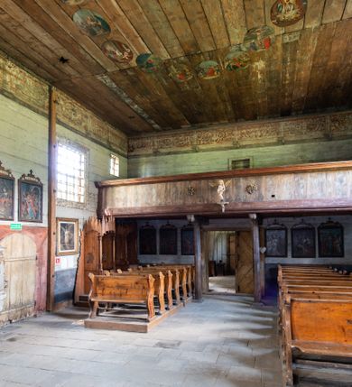 Zdjęcie nr 11: Kościół jest usytuowany ustronnie na stoku wzniesienia, otoczony starodrzewiem i parkanem, ujmującym stary cmentarz z nielicznymi mogiłami i nagrobkami. Orientowaną świątynię w całości wzniesiono z drewna. Zastosowano konstrukcję zrębową na murowanej podwalinie z murowaną kryptą pod prezbiterium. Nawa kościoła jest prawie kwadratowa. Od wchodu przylega do niej węższe prezbiterium zamknięte trójbocznie. Przy jego północnej ścianie wzniesiono bezokienną zakrystię z wejściem od strony wschodniej. Od zachodu z nawą łączy się wieża na rzucie kwadratu wzniesiona na tzw. słup. Ma pochyłe ściany, szalowane w dolnej części deskami, a w górnej podbite gontem. Wieża zakończona jest nadwieszoną izbicą, zwieńczoną ostrosłupowym hełmem gontowym. W połowie wysokości wieżę opasa pulpitowy daszek gontowy łączący się po bokach z dachem nawy. Pod wieżą urządzono obszerną kruchtę. Wysokie i spadziste dachy kościoła pokryte są gontem. Więźba ma konstrukcję storczykową. Ponad wschodnim szczytem nawy usytuowano nadwieszoną wieżyczkę na sygnaturkę o kształcie cebulastym z latarnią zwieńczoną krzyżem. Całość bryły kościoła (z wyjątkiem wieży) obiegają otwarte soboty, w które przed zakrystią od wschodu wbudowano nowy przedsionek. W nawie od południa znajduje się profilowany portal z nadprożem wykrojonym w ośli grzbiet. Umieszczone w nim drzwi zostały zaopatrzone w stare okucia i antabę. Wnętrze nawy i prezbiterium nakryto płaskimi stropami z pozostałościami późnorenesansowych malowideł z motywem kasetonów z rozetami. Łuk tęczowy jest ostry. Spływa na profilowaną belkę, która jest wsparta na kroksztynach. Na belce tęczowej został ustawiony krucyfiks oraz figury Matki Boskiej i św. Jana Apostoła. Chór muzyczny z dekorowanym malarsko parapetem został wsparty na dwóch słupach. W świątyni znajduje się rokokowy ołtarz główny z obrazem ze sceną Zwiastowania NMP. Dwa ołtarze boczne ustawione zostały przy łuku tęczowym. Prawy ołtarz boczny św. Karola Boromeusza pochodzi z drugiej połowy XVII wieku. Na to miejsce trafił on w połowie XX wieku z kaplicy pałacu w Osieku. Lewy ołtarz boczny jest późnobarokowy z około 1700 roku. W jego centrum umieszczono obraz Matki Boskiej Piekarskiej. Na północnej ścianie nad wejściem do zakrystii zawieszono epitafium Mikołaja i Beaty z Mirowa Porębskich z 1611 roku. Wcześniej epitafium pełniło rolę retabulum w miejscu stojącego dziś ołtarza św. Karola Boromeusza. W prezbiterium przy łuku tęczowym zawieszono rokokową ambonę w kształcie łodzi, na którą wejście prowadzi z zakrystii. Przy wejściu do nawy znajduje się kamienna chrzcielnica z początku XVI wieku, ozdobiona herbem Fogelweder, z drewnianą, późnobarokową nakrywą. W zakrystii zachował się także rokokowy drewniany lawetarz z drugiej połowy XVIII wieku.     