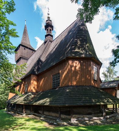 Zdjęcie nr 6: Kościół jest usytuowany ustronnie na stoku wzniesienia, otoczony starodrzewiem i parkanem, ujmującym stary cmentarz z nielicznymi mogiłami i nagrobkami. Orientowaną świątynię w całości wzniesiono z drewna. Zastosowano konstrukcję zrębową na murowanej podwalinie z murowaną kryptą pod prezbiterium. Nawa kościoła jest prawie kwadratowa. Od wchodu przylega do niej węższe prezbiterium zamknięte trójbocznie. Przy jego północnej ścianie wzniesiono bezokienną zakrystię z wejściem od strony wschodniej. Od zachodu z nawą łączy się wieża na rzucie kwadratu wzniesiona na tzw. słup. Ma pochyłe ściany, szalowane w dolnej części deskami, a w górnej podbite gontem. Wieża zakończona jest nadwieszoną izbicą, zwieńczoną ostrosłupowym hełmem gontowym. W połowie wysokości wieżę opasa pulpitowy daszek gontowy łączący się po bokach z dachem nawy. Pod wieżą urządzono obszerną kruchtę. Wysokie i spadziste dachy kościoła pokryte są gontem. Więźba ma konstrukcję storczykową. Ponad wschodnim szczytem nawy usytuowano nadwieszoną wieżyczkę na sygnaturkę o kształcie cebulastym z latarnią zwieńczoną krzyżem. Całość bryły kościoła (z wyjątkiem wieży) obiegają otwarte soboty, w które przed zakrystią od wschodu wbudowano nowy przedsionek. W nawie od południa znajduje się profilowany portal z nadprożem wykrojonym w ośli grzbiet. Umieszczone w nim drzwi zostały zaopatrzone w stare okucia i antabę. Wnętrze nawy i prezbiterium nakryto płaskimi stropami z pozostałościami późnorenesansowych malowideł z motywem kasetonów z rozetami. Łuk tęczowy jest ostry. Spływa na profilowaną belkę, która jest wsparta na kroksztynach. Na belce tęczowej został ustawiony krucyfiks oraz figury Matki Boskiej i św. Jana Apostoła. Chór muzyczny z dekorowanym malarsko parapetem został wsparty na dwóch słupach. W świątyni znajduje się rokokowy ołtarz główny z obrazem ze sceną Zwiastowania NMP. Dwa ołtarze boczne ustawione zostały przy łuku tęczowym. Prawy ołtarz boczny św. Karola Boromeusza pochodzi z drugiej połowy XVII wieku. Na to miejsce trafił on w połowie XX wieku z kaplicy pałacu w Osieku. Lewy ołtarz boczny jest późnobarokowy z około 1700 roku. W jego centrum umieszczono obraz Matki Boskiej Piekarskiej. Na północnej ścianie nad wejściem do zakrystii zawieszono epitafium Mikołaja i Beaty z Mirowa Porębskich z 1611 roku. Wcześniej epitafium pełniło rolę retabulum w miejscu stojącego dziś ołtarza św. Karola Boromeusza. W prezbiterium przy łuku tęczowym zawieszono rokokową ambonę w kształcie łodzi, na którą wejście prowadzi z zakrystii. Przy wejściu do nawy znajduje się kamienna chrzcielnica z początku XVI wieku, ozdobiona herbem Fogelweder, z drewnianą, późnobarokową nakrywą. W zakrystii zachował się także rokokowy drewniany lawetarz z drugiej połowy XVIII wieku.     
