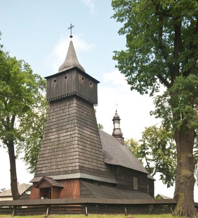 Zdjęcie nr 3: Drewnianą architekturę kościoła charakteryzuje konstrukcja zrębowa. Bryłę świątyni tworzy korpus nawowy oraz węższe, zakończone trójbocznie prezbiterium z przylegającą od północy zakrystią. Od zachodu do korpusu dostawiono wieżę o konstrukcji słupowo-ramowej z izbicą, zwieńczoną cebulastym hełmem przechodzącym w ostrosłup. Ściany pokryte są gontem, izbica wieży pionowym szalunkiem z listwowaniem, dekoracyjnym wycięciem oraz okrągłymi otworami. Korpus nawowy i prezbiterium nakrywają oddzielne, wielopołaciowe dachy o zróżnicowanej wysokości kalenicy, kryte blachą. Wokół bryły kościoła znajdują się otwarte soboty z wydatnymi dachami gontowymi. 
Wnętrze świątyni przekrywają płaskie stropy wydzielone profilowanym gzymsem. Otwory drzwiowe ujęte są późnogotyckimi portalami o nadprożach w formie tzw. łuku w ośli grzbiet. Profilowany łuk tęczowy ma kształt półokrągły i jest nadwieszony na kroksztynach. Ściany i stropy pokryte są polichromią.       
