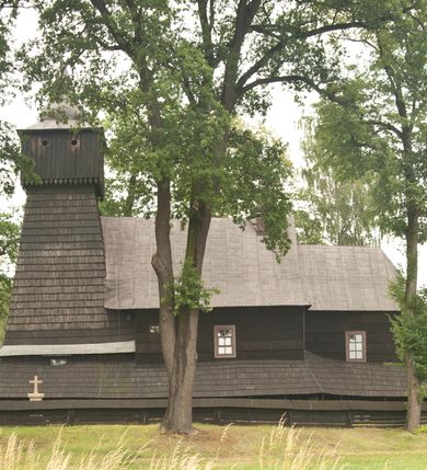 Zdjęcie nr 2: Drewnianą architekturę kościoła charakteryzuje konstrukcja zrębowa. Bryłę świątyni tworzy korpus nawowy oraz węższe, zakończone trójbocznie prezbiterium z przylegającą od północy zakrystią. Od zachodu do korpusu dostawiono wieżę o konstrukcji słupowo-ramowej z izbicą, zwieńczoną cebulastym hełmem przechodzącym w ostrosłup. Ściany pokryte są gontem, izbica wieży pionowym szalunkiem z listwowaniem, dekoracyjnym wycięciem oraz okrągłymi otworami. Korpus nawowy i prezbiterium nakrywają oddzielne, wielopołaciowe dachy o zróżnicowanej wysokości kalenicy, kryte blachą. Wokół bryły kościoła znajdują się otwarte soboty z wydatnymi dachami gontowymi. 
Wnętrze świątyni przekrywają płaskie stropy wydzielone profilowanym gzymsem. Otwory drzwiowe ujęte są późnogotyckimi portalami o nadprożach w formie tzw. łuku w ośli grzbiet. Profilowany łuk tęczowy ma kształt półokrągły i jest nadwieszony na kroksztynach. Ściany i stropy pokryte są polichromią.       
