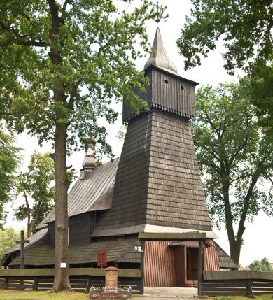 Zdjęcie nr 4: Drewnianą architekturę kościoła charakteryzuje konstrukcja zrębowa. Bryłę świątyni tworzy korpus nawowy oraz węższe, zakończone trójbocznie prezbiterium z przylegającą od północy zakrystią. Od zachodu do korpusu dostawiono wieżę o konstrukcji słupowo-ramowej z izbicą, zwieńczoną cebulastym hełmem przechodzącym w ostrosłup. Ściany pokryte są gontem, izbica wieży pionowym szalunkiem z listwowaniem, dekoracyjnym wycięciem oraz okrągłymi otworami. Korpus nawowy i prezbiterium nakrywają oddzielne, wielopołaciowe dachy o zróżnicowanej wysokości kalenicy, kryte blachą. Wokół bryły kościoła znajdują się otwarte soboty z wydatnymi dachami gontowymi. 
Wnętrze świątyni przekrywają płaskie stropy wydzielone profilowanym gzymsem. Otwory drzwiowe ujęte są późnogotyckimi portalami o nadprożach w formie tzw. łuku w ośli grzbiet. Profilowany łuk tęczowy ma kształt półokrągły i jest nadwieszony na kroksztynach. Ściany i stropy pokryte są polichromią.       
