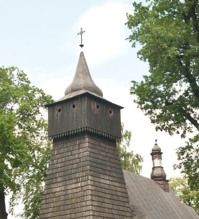 Zdjęcie nr 1: Drewnianą architekturę kościoła charakteryzuje konstrukcja zrębowa. Bryłę świątyni tworzy korpus nawowy oraz węższe, zakończone trójbocznie prezbiterium z przylegającą od północy zakrystią. Od zachodu do korpusu dostawiono wieżę o konstrukcji słupowo-ramowej z izbicą, zwieńczoną cebulastym hełmem przechodzącym w ostrosłup. Ściany pokryte są gontem, izbica wieży pionowym szalunkiem z listwowaniem, dekoracyjnym wycięciem oraz okrągłymi otworami. Korpus nawowy i prezbiterium nakrywają oddzielne, wielopołaciowe dachy o zróżnicowanej wysokości kalenicy, kryte blachą. Wokół bryły kościoła znajdują się otwarte soboty z wydatnymi dachami gontowymi. 
Wnętrze świątyni przekrywają płaskie stropy wydzielone profilowanym gzymsem. Otwory drzwiowe ujęte są późnogotyckimi portalami o nadprożach w formie tzw. łuku w ośli grzbiet. Profilowany łuk tęczowy ma kształt półokrągły i jest nadwieszony na kroksztynach. Ściany i stropy pokryte są polichromią.       

