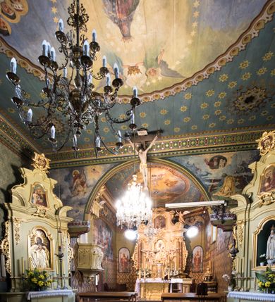 Zdjęcie nr 10: Drewnianą architekturę kościoła charakteryzuje konstrukcja zrębowa. Bryłę świątyni tworzy korpus nawowy oraz węższe, zakończone trójbocznie prezbiterium z przylegającą od północy zakrystią. Od zachodu do korpusu dostawiono wieżę o konstrukcji słupowo-ramowej z izbicą, zwieńczoną cebulastym hełmem przechodzącym w ostrosłup. Ściany pokryte są gontem, izbica wieży pionowym szalunkiem z listwowaniem, dekoracyjnym wycięciem oraz okrągłymi otworami. Korpus nawowy i prezbiterium nakrywają oddzielne, wielopołaciowe dachy o zróżnicowanej wysokości kalenicy, kryte blachą. Wokół bryły kościoła znajdują się otwarte soboty z wydatnymi dachami gontowymi. 
Wnętrze świątyni przekrywają płaskie stropy wydzielone profilowanym gzymsem. Otwory drzwiowe ujęte są późnogotyckimi portalami o nadprożach w formie tzw. łuku w ośli grzbiet. Profilowany łuk tęczowy ma kształt półokrągły i jest nadwieszony na kroksztynach. Ściany i stropy pokryte są polichromią.       
