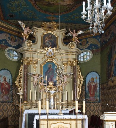 Zdjęcie nr 11: Drewnianą architekturę kościoła charakteryzuje konstrukcja zrębowa. Bryłę świątyni tworzy korpus nawowy oraz węższe, zakończone trójbocznie prezbiterium z przylegającą od północy zakrystią. Od zachodu do korpusu dostawiono wieżę o konstrukcji słupowo-ramowej z izbicą, zwieńczoną cebulastym hełmem przechodzącym w ostrosłup. Ściany pokryte są gontem, izbica wieży pionowym szalunkiem z listwowaniem, dekoracyjnym wycięciem oraz okrągłymi otworami. Korpus nawowy i prezbiterium nakrywają oddzielne, wielopołaciowe dachy o zróżnicowanej wysokości kalenicy, kryte blachą. Wokół bryły kościoła znajdują się otwarte soboty z wydatnymi dachami gontowymi. 
Wnętrze świątyni przekrywają płaskie stropy wydzielone profilowanym gzymsem. Otwory drzwiowe ujęte są późnogotyckimi portalami o nadprożach w formie tzw. łuku w ośli grzbiet. Profilowany łuk tęczowy ma kształt półokrągły i jest nadwieszony na kroksztynach. Ściany i stropy pokryte są polichromią.       
