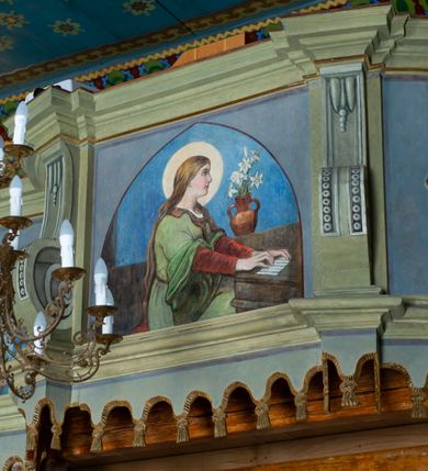 Zdjęcie nr 21: Drewnianą architekturę kościoła charakteryzuje konstrukcja zrębowa. Bryłę świątyni tworzy korpus nawowy oraz węższe, zakończone trójbocznie prezbiterium z przylegającą od północy zakrystią. Od zachodu do korpusu dostawiono wieżę o konstrukcji słupowo-ramowej z izbicą, zwieńczoną cebulastym hełmem przechodzącym w ostrosłup. Ściany pokryte są gontem, izbica wieży pionowym szalunkiem z listwowaniem, dekoracyjnym wycięciem oraz okrągłymi otworami. Korpus nawowy i prezbiterium nakrywają oddzielne, wielopołaciowe dachy o zróżnicowanej wysokości kalenicy, kryte blachą. Wokół bryły kościoła znajdują się otwarte soboty z wydatnymi dachami gontowymi. 
Wnętrze świątyni przekrywają płaskie stropy wydzielone profilowanym gzymsem. Otwory drzwiowe ujęte są późnogotyckimi portalami o nadprożach w formie tzw. łuku w ośli grzbiet. Profilowany łuk tęczowy ma kształt półokrągły i jest nadwieszony na kroksztynach. Ściany i stropy pokryte są polichromią.       
