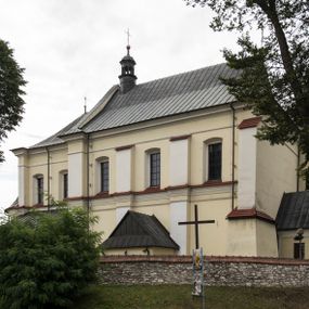 Zdjęcie nr 1: Kościół jest położony w centrum wsi, na wschód od głównej drogi, na placu otoczonym kamiennym murem przykrytym dachówką, z kilkoma drzewami. Wejście na plac przykościelny prowadzi przez szerokie schody i bramę od zachodu i bramkę od północy. Kościół jest budowlą założoną na planie prostokąta, jednonawowy, trójprzęsłowy z węższym, dwuprzęsłowym prezbiterium z apsydą. Do nawy przylegają od zachodu i północy dwie kruchty na planie kwadratu i wieża w narożu południowo-zachodnim fasady. Do prezbiterium od północy jest dostawiona kaplica na rzucie prostokąta otwierająca się półkolistymi arkadami, a od południa zakrystia. 
Artykulacja ścian jest przeprowadzona za pomocą zdwojonych pilastrów toskańskich stojących na wysokich postumentach i podtrzymujących wydatne, przełamujące się, pełne belkowanie z fryzem tryglifowym oraz wysuniętym gzymsem, obiegającym całe wnętrze świątyni. Wnętrze nakrywa sklepienie kolebkowe na gurtach z lunetami; w kluczach sklepienia znajdują się tarcze herbowe, Złota Pilawa oraz Ostoja. W lunetach umieszczone są okna prostokątne zamknięte łukiem odcinkowym; takie same okna znajdują się w apsydzie prezbiterium, poniżej belkowania.  W kaplicy znajdują się dwa prostokątne okna zamknięte odcinkowo. Zakrystia jest jednoprzestrzenna, nakryta sklepieniem krzyżowym. Prowadzi do niej kamienny portal profilowany z uszakami, z podwieszonymi wolutami, zwieńczony wydatnym gzymsem. W partii fryzu umieszczono polichromowany kartusz z herbem Ostoja. W ścianach środkowego przęsła korpusu nawowego po obu stronach kościoła znajdują się głębokie, prostokątne nisze zamknięte łukami odcinkowymi. W niszy północnej umieszczono drzwi prowadzące do niewielkiej kruchty przykrytej stropem, z dwoma małymi, okrągłymi oknami po bokach. Również po zachodniej stronie korpusu znajduje się wejście do kruchty. Ponadto na ścianach nawy oraz prezbiterium widnieją płyciny ujęte ramą profilowaną w tynku. W pierwszym od strony fasady przęśle znajduje się murowany chór muzyczny, trójarkadowy, wsparty na dwóch filarach opiętych pilastrami oraz dwóch półfilarach przylegających do ścian, sklepiony krzyżowo. 
Fasada kościoła jest płaska, zakończona gzymsem, z czterokondygnacyjną wieżą, nakrytą cebulastym hełmem z krzyżem. Boczne elewacje ujęte uskokowymi przyporami, zakończone gzymsem. Dachy dwuspadowe nad nawą i kruchtami, trójspadowe nad prezbiterium, półsferyczne nad apsydą, pulpitowe nad kaplicą i zakrystią, kryte blachą. Nad granicy nawy i prezbiterium wieloboczna wieżyczka na sygnaturkę z prześwitami, zakończona kopułą, sterczyną i kulą z krzyżem. 
