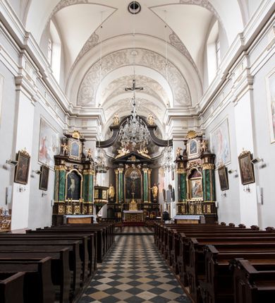 Zdjęcie nr 18: Kościół jest położony w centrum wsi, na wschód od głównej drogi, na placu otoczonym kamiennym murem przykrytym dachówką, z kilkoma drzewami. Wejście na plac przykościelny prowadzi przez szerokie schody i bramę od zachodu i bramkę od północy. Kościół jest budowlą założoną na planie prostokąta, jednonawowy, trójprzęsłowy z węższym, dwuprzęsłowym prezbiterium z apsydą. Do nawy przylegają od zachodu i północy dwie kruchty na planie kwadratu i wieża w narożu południowo-zachodnim fasady. Do prezbiterium od północy jest dostawiona kaplica na rzucie prostokąta otwierająca się półkolistymi arkadami, a od południa zakrystia. 
Artykulacja ścian jest przeprowadzona za pomocą zdwojonych pilastrów toskańskich stojących na wysokich postumentach i podtrzymujących wydatne, przełamujące się, pełne belkowanie z fryzem tryglifowym oraz wysuniętym gzymsem, obiegającym całe wnętrze świątyni. Wnętrze nakrywa sklepienie kolebkowe na gurtach z lunetami; w kluczach sklepienia znajdują się tarcze herbowe, Złota Pilawa oraz Ostoja. W lunetach umieszczone są okna prostokątne zamknięte łukiem odcinkowym; takie same okna znajdują się w apsydzie prezbiterium, poniżej belkowania.  W kaplicy znajdują się dwa prostokątne okna zamknięte odcinkowo. Zakrystia jest jednoprzestrzenna, nakryta sklepieniem krzyżowym. Prowadzi do niej kamienny portal profilowany z uszakami, z podwieszonymi wolutami, zwieńczony wydatnym gzymsem. W partii fryzu umieszczono polichromowany kartusz z herbem Ostoja. W ścianach środkowego przęsła korpusu nawowego po obu stronach kościoła znajdują się głębokie, prostokątne nisze zamknięte łukami odcinkowymi. W niszy północnej umieszczono drzwi prowadzące do niewielkiej kruchty przykrytej stropem, z dwoma małymi, okrągłymi oknami po bokach. Również po zachodniej stronie korpusu znajduje się wejście do kruchty. Ponadto na ścianach nawy oraz prezbiterium widnieją płyciny ujęte ramą profilowaną w tynku. W pierwszym od strony fasady przęśle znajduje się murowany chór muzyczny, trójarkadowy, wsparty na dwóch filarach opiętych pilastrami oraz dwóch półfilarach przylegających do ścian, sklepiony krzyżowo. 
Fasada kościoła jest płaska, zakończona gzymsem, z czterokondygnacyjną wieżą, nakrytą cebulastym hełmem z krzyżem. Boczne elewacje ujęte uskokowymi przyporami, zakończone gzymsem. Dachy dwuspadowe nad nawą i kruchtami, trójspadowe nad prezbiterium, półsferyczne nad apsydą, pulpitowe nad kaplicą i zakrystią, kryte blachą. Nad granicy nawy i prezbiterium wieloboczna wieżyczka na sygnaturkę z prześwitami, zakończona kopułą, sterczyną i kulą z krzyżem. 
