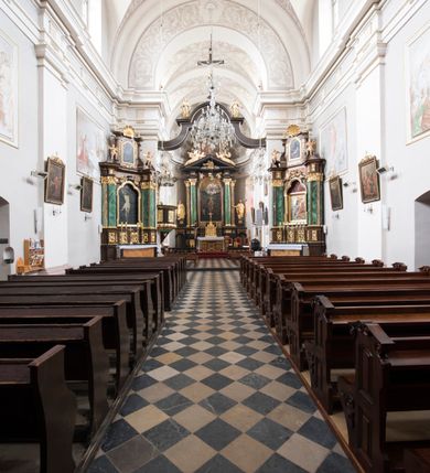 Zdjęcie nr 22: Kościół jest położony w centrum wsi, na wschód od głównej drogi, na placu otoczonym kamiennym murem przykrytym dachówką, z kilkoma drzewami. Wejście na plac przykościelny prowadzi przez szerokie schody i bramę od zachodu i bramkę od północy. Kościół jest budowlą założoną na planie prostokąta, jednonawowy, trójprzęsłowy z węższym, dwuprzęsłowym prezbiterium z apsydą. Do nawy przylegają od zachodu i północy dwie kruchty na planie kwadratu i wieża w narożu południowo-zachodnim fasady. Do prezbiterium od północy jest dostawiona kaplica na rzucie prostokąta otwierająca się półkolistymi arkadami, a od południa zakrystia. 
Artykulacja ścian jest przeprowadzona za pomocą zdwojonych pilastrów toskańskich stojących na wysokich postumentach i podtrzymujących wydatne, przełamujące się, pełne belkowanie z fryzem tryglifowym oraz wysuniętym gzymsem, obiegającym całe wnętrze świątyni. Wnętrze nakrywa sklepienie kolebkowe na gurtach z lunetami; w kluczach sklepienia znajdują się tarcze herbowe, Złota Pilawa oraz Ostoja. W lunetach umieszczone są okna prostokątne zamknięte łukiem odcinkowym; takie same okna znajdują się w apsydzie prezbiterium, poniżej belkowania.  W kaplicy znajdują się dwa prostokątne okna zamknięte odcinkowo. Zakrystia jest jednoprzestrzenna, nakryta sklepieniem krzyżowym. Prowadzi do niej kamienny portal profilowany z uszakami, z podwieszonymi wolutami, zwieńczony wydatnym gzymsem. W partii fryzu umieszczono polichromowany kartusz z herbem Ostoja. W ścianach środkowego przęsła korpusu nawowego po obu stronach kościoła znajdują się głębokie, prostokątne nisze zamknięte łukami odcinkowymi. W niszy północnej umieszczono drzwi prowadzące do niewielkiej kruchty przykrytej stropem, z dwoma małymi, okrągłymi oknami po bokach. Również po zachodniej stronie korpusu znajduje się wejście do kruchty. Ponadto na ścianach nawy oraz prezbiterium widnieją płyciny ujęte ramą profilowaną w tynku. W pierwszym od strony fasady przęśle znajduje się murowany chór muzyczny, trójarkadowy, wsparty na dwóch filarach opiętych pilastrami oraz dwóch półfilarach przylegających do ścian, sklepiony krzyżowo. 
Fasada kościoła jest płaska, zakończona gzymsem, z czterokondygnacyjną wieżą, nakrytą cebulastym hełmem z krzyżem. Boczne elewacje ujęte uskokowymi przyporami, zakończone gzymsem. Dachy dwuspadowe nad nawą i kruchtami, trójspadowe nad prezbiterium, półsferyczne nad apsydą, pulpitowe nad kaplicą i zakrystią, kryte blachą. Nad granicy nawy i prezbiterium wieloboczna wieżyczka na sygnaturkę z prześwitami, zakończona kopułą, sterczyną i kulą z krzyżem. 
