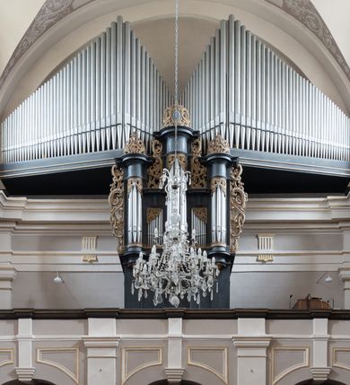 Zdjęcie nr 10: Kościół jest położony w centrum wsi, na wschód od głównej drogi, na placu otoczonym kamiennym murem przykrytym dachówką, z kilkoma drzewami. Wejście na plac przykościelny prowadzi przez szerokie schody i bramę od zachodu i bramkę od północy. Kościół jest budowlą założoną na planie prostokąta, jednonawowy, trójprzęsłowy z węższym, dwuprzęsłowym prezbiterium z apsydą. Do nawy przylegają od zachodu i północy dwie kruchty na planie kwadratu i wieża w narożu południowo-zachodnim fasady. Do prezbiterium od północy jest dostawiona kaplica na rzucie prostokąta otwierająca się półkolistymi arkadami, a od południa zakrystia. 
Artykulacja ścian jest przeprowadzona za pomocą zdwojonych pilastrów toskańskich stojących na wysokich postumentach i podtrzymujących wydatne, przełamujące się, pełne belkowanie z fryzem tryglifowym oraz wysuniętym gzymsem, obiegającym całe wnętrze świątyni. Wnętrze nakrywa sklepienie kolebkowe na gurtach z lunetami; w kluczach sklepienia znajdują się tarcze herbowe, Złota Pilawa oraz Ostoja. W lunetach umieszczone są okna prostokątne zamknięte łukiem odcinkowym; takie same okna znajdują się w apsydzie prezbiterium, poniżej belkowania.  W kaplicy znajdują się dwa prostokątne okna zamknięte odcinkowo. Zakrystia jest jednoprzestrzenna, nakryta sklepieniem krzyżowym. Prowadzi do niej kamienny portal profilowany z uszakami, z podwieszonymi wolutami, zwieńczony wydatnym gzymsem. W partii fryzu umieszczono polichromowany kartusz z herbem Ostoja. W ścianach środkowego przęsła korpusu nawowego po obu stronach kościoła znajdują się głębokie, prostokątne nisze zamknięte łukami odcinkowymi. W niszy północnej umieszczono drzwi prowadzące do niewielkiej kruchty przykrytej stropem, z dwoma małymi, okrągłymi oknami po bokach. Również po zachodniej stronie korpusu znajduje się wejście do kruchty. Ponadto na ścianach nawy oraz prezbiterium widnieją płyciny ujęte ramą profilowaną w tynku. W pierwszym od strony fasady przęśle znajduje się murowany chór muzyczny, trójarkadowy, wsparty na dwóch filarach opiętych pilastrami oraz dwóch półfilarach przylegających do ścian, sklepiony krzyżowo. 
Fasada kościoła jest płaska, zakończona gzymsem, z czterokondygnacyjną wieżą, nakrytą cebulastym hełmem z krzyżem. Boczne elewacje ujęte uskokowymi przyporami, zakończone gzymsem. Dachy dwuspadowe nad nawą i kruchtami, trójspadowe nad prezbiterium, półsferyczne nad apsydą, pulpitowe nad kaplicą i zakrystią, kryte blachą. Nad granicy nawy i prezbiterium wieloboczna wieżyczka na sygnaturkę z prześwitami, zakończona kopułą, sterczyną i kulą z krzyżem. 
