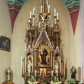 Zdjęcie nr 1: Ołtarz drewniany, prostopadłościenny, na dwustopniowej podstawie; mensa drewniana; antependium podzielone na trzy kwadratowe pola wypełnione maswerkami. 

Tabernakulum w formie prostopadłościennej skrzynki. Ścianka frontowa flankowana dwiema lizenami dźwigającymi niepełne belkowanie wyłamane nad osią środkową, opasujące tabernakulum z trzech stron, z fryzem dekorowanym maswerkowymi czwórliśćmi. Drzwiczki w formie stojącego prostokąta, zamkniętego łukiem ostrym z płaskorzeźbionym krzyżem w polu. 

Nastawa architektoniczna, jednoosiowa, jednokondygnacyjna ze zwieńczeniem, z predellą. Kondygnacja ujęta parą dwustrefowych kapliczek: w dolnej części, w niszach zwieńczonych wimpergą figury św. Wojciecha i św. Stanisława; w górnej zamknięte od góry baldachimem z ażurową fialą, zdobioną maswerkiem, sterczynami i wimpergami. Pole środkowe nastawy na cokole, ujęte wysokimi, wąskimi kolumienkami podtrzymującymi ostrołukową arkadę z niszą, zwieńczoną wimpergą. Wimperga wypełniona maswerkiem z czwórliściem pośrodku. W niszy obraz św. Antoniego Padewskiego, na zasuwie obraz Jezusa Miłosiernego. Kondygnację ujmują uszy w postaci łuków przyporowych, zdobionych ażurowymi blendami i sterczynami. Zwieńczenie w formie wieżyczki flankowane łukami przyporowymi, zakończone wysoką fialą z kwiatonem.

Struktura w kolorze naturalnego drewna, płyciny polichromowane na czerwono i niebiesko; kolumienki, ornamentyka, profile i detale architektoniczne złocone.
