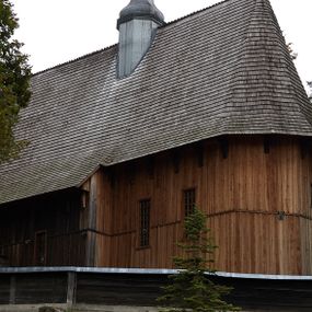 Zdjęcie nr 1: Kościół drewniany, orientowany, usytuowany na wzgórku, otoczony pierwotnym cmentarzem przykościelnym oraz starodrzewiem (lipami), ujęty drewnianym ogrodzeniem z poziomo ułożonych desek, w którego ciągu znajduje się masywna dzwonnica. Ściany kościoła wzniesione w konstrukcji zrębowej, oszalowanej pionowo z listwowaniem. Nawa na planie prostokąta; prezbiterium węższe, zamknięte wielobocznie, zbudowane na zrąb; od północy zakrystia na planie prostokąta; od południa późniejsza, dobudowana kruchta. Od zachodu nawę poprzedza niższa wieża, zbudowana w konstrukcji słupowo-ramowej, o pochyłych ścianach. Wnętrze nakryte stropami, w nawie z zaskrzynieniami. Nawa od prezbiterium oddzielona tęczą o łuku półkolistym wspartym na kroksztynach; na belce umieszczone rzeźby z początku XVI wieku przedstawiające grupę Ukrzyżowania: krucyfiks, Matka Boska, św. Jan Ewangelista oraz św. Maria Magdalena. Chór muzyczny wsparty na dwóch kolumnach, barokowy. Wnętrze pokryte polichromią z pierwszej połowy XVII wieku. Pośrodku kościoła oraz bliżej chóru muzycznego znajdują się wejścia do krypt pokryte płytami. Główny portal kościoła umieszczony jest od strony zachodniej, w przedsionku pod wieżą, ukształtowany w formie profilowanej, lekko zaostrzonej arkady przechodzącej w tzw. ośli grzbiet. Portal południowy, w kruchcie zakończony ostrołukiem, z motywem sznura w profilowaniach z pierwotnymi jednoskrzydłowymi drzwiami o gotyckich okuciach. Portal prowadzący z prezbiterium do zakrystii ma bogate profilowanie (zewnętrzny profil z motywem „ząbków”), jest zakończony w tzw. ośli grzbiet z drzwiami żelaznymi, dekorowanymi ukośną kratą. Okna znajdują się od strony południowej, pod dwa w nawie oraz w prezbiterium. Nadokienniki mają wykrój w ośli grzbiet. Ponadto jedno okno o analogicznym układzie w prezbiterium na ścianie wschodniej, częściowo zabudowane, zasłonięte ołtarzem. Dach gontowy o jednej kalenicy, wsparty na kroksztynach z szerokim okapem, o dużym kącie spadku uzyskanym poprzez zastosowaną gotycką więźbę storczykową, pośrodku z wieżyczką na sygnaturkę o barkowym kształcie. Wieża główna nakryta dachem gontowym, trójspadowym.
