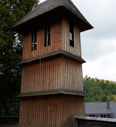 Zdjęcie nr 2: Kościół drewniany, orientowany, usytuowany na wzgórku, otoczony pierwotnym cmentarzem przykościelnym oraz starodrzewiem (lipami), ujęty drewnianym ogrodzeniem z poziomo ułożonych desek, w którego ciągu znajduje się masywna dzwonnica. Ściany kościoła wzniesione w konstrukcji zrębowej, oszalowanej pionowo z listwowaniem. Nawa na planie prostokąta; prezbiterium węższe, zamknięte wielobocznie, zbudowane na zrąb; od północy zakrystia na planie prostokąta; od południa późniejsza, dobudowana kruchta. Od zachodu nawę poprzedza niższa wieża, zbudowana w konstrukcji słupowo-ramowej, o pochyłych ścianach. Wnętrze nakryte stropami, w nawie z zaskrzynieniami. Nawa od prezbiterium oddzielona tęczą o łuku półkolistym wspartym na kroksztynach; na belce umieszczone rzeźby z początku XVI wieku przedstawiające grupę Ukrzyżowania: krucyfiks, Matka Boska, św. Jan Ewangelista oraz św. Maria Magdalena. Chór muzyczny wsparty na dwóch kolumnach, barokowy. Wnętrze pokryte polichromią z pierwszej połowy XVII wieku. Pośrodku kościoła oraz bliżej chóru muzycznego znajdują się wejścia do krypt pokryte płytami. Główny portal kościoła umieszczony jest od strony zachodniej, w przedsionku pod wieżą, ukształtowany w formie profilowanej, lekko zaostrzonej arkady przechodzącej w tzw. ośli grzbiet. Portal południowy, w kruchcie zakończony ostrołukiem, z motywem sznura w profilowaniach z pierwotnymi jednoskrzydłowymi drzwiami o gotyckich okuciach. Portal prowadzący z prezbiterium do zakrystii ma bogate profilowanie (zewnętrzny profil z motywem „ząbków”), jest zakończony w tzw. ośli grzbiet z drzwiami żelaznymi, dekorowanymi ukośną kratą. Okna znajdują się od strony południowej, pod dwa w nawie oraz w prezbiterium. Nadokienniki mają wykrój w ośli grzbiet. Ponadto jedno okno o analogicznym układzie w prezbiterium na ścianie wschodniej, częściowo zabudowane, zasłonięte ołtarzem. Dach gontowy o jednej kalenicy, wsparty na kroksztynach z szerokim okapem, o dużym kącie spadku uzyskanym poprzez zastosowaną gotycką więźbę storczykową, pośrodku z wieżyczką na sygnaturkę o barkowym kształcie. Wieża główna nakryta dachem gontowym, trójspadowym.
