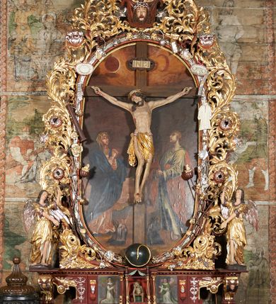 Zdjęcie nr 1: Nastawa ołtarzowa jednoosiowa, jednokondygnacyjna. Ołtarz prostopadłościenny, drewniany. Mensa z przodu dekorowana płyciną w kształcie prostokąta leżącego, malowaną na czerwono, w polu dwie gałązki palmowe i monogram IHS. Nastawa ustawiona jest na niskiej, trójosiowej predelli. Na osi głównej niewielkie tempietto, wsparte sześcioma kolumienkami z figurą Chrystusa Frasobliwego wewnątrz. Po bokach dwa obrazki z klęczącymi postaciami aniołów. Na osiach bocznych spływy wolutowe z półleżącymi postaciami aniołów oraz konsolki zdobione uskrzydlonymi główkami aniołków, skierowanymi na wprost. Predella podtrzymuje krucyfiks ustawiony na tle owalnego obrazu z Grupą Ukrzyżowania, obwiedzionego dokoła ramą z narzędziami Męki Pańskiej oraz bujną dekoracją ornamentu akantowego. Insygnia Arma Christii, kolejno od dołu, po lewej: obcęgi i młotek, pochodnia, włócznia z łańcuchem, kolumna, miecz z uchem Malchusa, rękawica, misa Piłata, Veraicon, misa z kośćmi do gry, suknia i drabina w jej tle, dzban Piłata, łańcuch i trzcina. U stóp krzyża napis: „Altare Confraternitatis Paupertatis Jesu Anno Dni 1703”. Po bokach dwie rzeźby aniołów. U dołu krzyża glob ziemski, opleciony przez węża; u góry na szczycie Veraikon i tarcza herbowa z herbem Szreniawa i literami „A. S. P. R.”. Dekoracja ornamentalna predelli okuciowa z kaboszonami, w kondygnacji akantowa. Polichromia struktury w kolorze bordowym, ornamentyka i profilowania złocone i srebrzone, detale czerwone.
