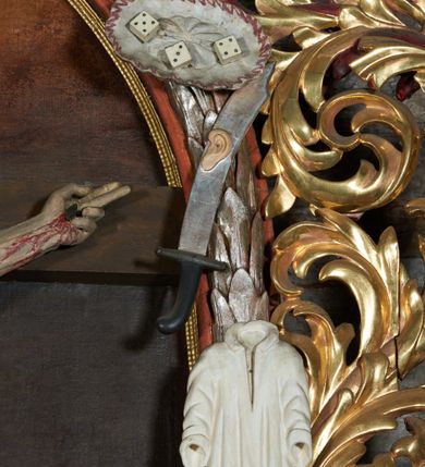 Zdjęcie nr 10: Nastawa ołtarzowa jednoosiowa, jednokondygnacyjna. Ołtarz prostopadłościenny, drewniany. Mensa z przodu dekorowana płyciną w kształcie prostokąta leżącego, malowaną na czerwono, w polu dwie gałązki palmowe i monogram IHS. Nastawa ustawiona jest na niskiej, trójosiowej predelli. Na osi głównej niewielkie tempietto, wsparte sześcioma kolumienkami z figurą Chrystusa Frasobliwego wewnątrz. Po bokach dwa obrazki z klęczącymi postaciami aniołów. Na osiach bocznych spływy wolutowe z półleżącymi postaciami aniołów oraz konsolki zdobione uskrzydlonymi główkami aniołków, skierowanymi na wprost. Predella podtrzymuje krucyfiks ustawiony na tle owalnego obrazu z Grupą Ukrzyżowania, obwiedzionego dokoła ramą z narzędziami Męki Pańskiej oraz bujną dekoracją ornamentu akantowego. Insygnia Arma Christii, kolejno od dołu, po lewej: obcęgi i młotek, pochodnia, włócznia z łańcuchem, kolumna, miecz z uchem Malchusa, rękawica, misa Piłata, Veraicon, misa z kośćmi do gry, suknia i drabina w jej tle, dzban Piłata, łańcuch i trzcina. U stóp krzyża napis: „Altare Confraternitatis Paupertatis Jesu Anno Dni 1703”. Po bokach dwie rzeźby aniołów. U dołu krzyża glob ziemski, opleciony przez węża; u góry na szczycie Veraikon i tarcza herbowa z herbem Szreniawa i literami „A. S. P. R.”. Dekoracja ornamentalna predelli okuciowa z kaboszonami, w kondygnacji akantowa. Polichromia struktury w kolorze bordowym, ornamentyka i profilowania złocone i srebrzone, detale czerwone.
