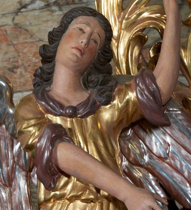 Zdjęcie nr 20: Nastawa ołtarzowa jednoosiowa, jednokondygnacyjna. Ołtarz prostopadłościenny, drewniany. Mensa z przodu dekorowana płyciną w kształcie prostokąta leżącego, malowaną na czerwono, w polu dwie gałązki palmowe i monogram IHS. Nastawa ustawiona jest na niskiej, trójosiowej predelli. Na osi głównej niewielkie tempietto, wsparte sześcioma kolumienkami z figurą Chrystusa Frasobliwego wewnątrz. Po bokach dwa obrazki z klęczącymi postaciami aniołów. Na osiach bocznych spływy wolutowe z półleżącymi postaciami aniołów oraz konsolki zdobione uskrzydlonymi główkami aniołków, skierowanymi na wprost. Predella podtrzymuje krucyfiks ustawiony na tle owalnego obrazu z Grupą Ukrzyżowania, obwiedzionego dokoła ramą z narzędziami Męki Pańskiej oraz bujną dekoracją ornamentu akantowego. Insygnia Arma Christii, kolejno od dołu, po lewej: obcęgi i młotek, pochodnia, włócznia z łańcuchem, kolumna, miecz z uchem Malchusa, rękawica, misa Piłata, Veraicon, misa z kośćmi do gry, suknia i drabina w jej tle, dzban Piłata, łańcuch i trzcina. U stóp krzyża napis: „Altare Confraternitatis Paupertatis Jesu Anno Dni 1703”. Po bokach dwie rzeźby aniołów. U dołu krzyża glob ziemski, opleciony przez węża; u góry na szczycie Veraikon i tarcza herbowa z herbem Szreniawa i literami „A. S. P. R.”. Dekoracja ornamentalna predelli okuciowa z kaboszonami, w kondygnacji akantowa. Polichromia struktury w kolorze bordowym, ornamentyka i profilowania złocone i srebrzone, detale czerwone.
