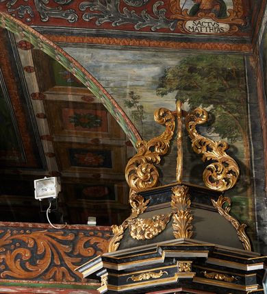 Zdjęcie nr 50: Polichromia ścienna prezbiterium pokrywa wszystkie ściany oraz strop tej części świątyni. 

Polichromia ścienna stropu
Strop zdobiony jest malowanymi kasetonami, w których umieszczone są rozety na różnokolorowych tłach. W centrum ukazane są dwie prostokątne kompozycje, ujęte w ornamentalne ramy. Od wschodu znajduje się Zwiastowanie Zachariaszowi, powyżej inskrypcja: „NE TIMEAS ZACHARIA VXOR TVA PARIET TIBI / FILIVM ET VOCABIS NOMEN EIVS IOANNEM LUCAE 1”. W drugiej kompozycji przedstawiono Nawiedzenie z Najświętszej Marii Panny ze św. Zachariaszem i św. Józefem, powyżej inskrypcja: „EXVLTAVIT IN GAVDIO INFANS IN VTERO MEO LUCAE 1”. 

Polichromia ścienna ścian prezbiterium
Dekoracje ścian o formie pasowej. W dolnej kondygnacji malowane iluzjonistycznie portrety świętych węgierskich w ornamentalnych ramach. Postacie ukazane do wysokości kolan, zwrócone trzy czwarte z odpowiednimi im atrybutami w dłoniach. Portrety opatrzone u góry łacińskimi opisami. Na ścianie północnej galerię otwiera wizerunek króla Stefana z napisem: „S(ANCTVS) STEPHANVS REX VNGARIAE, REGNVM SVVM DEIPARAE / DONAVIT OBIIT. 1038. 20 AVG(VSTVS) SEP. ALBERE 9.”. Następnie ukazani są kolejno: św. Emeryk „S(ANCTVS) EMERIGVS DVX VNGARIAE VT VIRGO MANERET, / A. CAELO PERSVASVS OBIIT. 1032. 5 nou. Sen. Albdvewas”, św. Władysław: „S(ANCTVS) LADISLAVS REX UNGARIAE ROSARIO ENSI OBVO/LUTO PVGNARE SOLITVS OBIIT 1097. 27.  iun. Sep. varad.”. Po drugiej stronie prezbiterium umieszczone są cztery obrazy świętych o tych samych wymiarach, również opatrzone napisami. Od lewej strony kolejno: św. Salomon „S(ANCTVS) SALOMON REX VNGARIAE DEIN EREMITA VITAE / AVSTERITATE FLORVIT OBIIT 1077. 28. Sept. Sep. Pold. in Idria”, św. Kazimierz: „S(ANCTVS) CASIMIRVS ELECTVS REX VNGARIAE AMORE / SARVANDAE VIRGINITATIS OBIIT 1484 4. MARTII.”, św. Dawid: „S(ANTCVS) DAVID REX SCOTIAE, FILIVS S(ANCTA) MARGA/RITAE VNGARA MATRE NATAE OBIIT 1153”, św. Ludwik: „S(SANCTVS) LVDOVICVS TOLOSANVS EP. E MARIA / REGIS VNG. FILIA NATVS OBIIT 1297 19 Aug(ustvs)”. Cykl ten kończy przy ścianie tęczowej przedstawienie św. Gintera „S(ANCVS) GVNTHERVS EREM. S(ANCTVS) STEPHANI REGIS / VNGARIAE COGNATVS OBIIT 1045 9. oct.”. Dodatkowo w obrazy wpisane są zacheuszki w formie równoramiennych krzyży ujętych w medaliony utworzone z wieńca. W zamknięciu prezbiterium przedstawienia diabłów, a od zachodu pod amboną czyściec.

Kondygnacja druga o podziałach architektonicznych u dołu wydzielona cokołem, dekorowanym złotymi girlandami na czarnym tle. Prostokątne pola wydzielone za pomocą malowanych iluzjonistycznie kolumn korynckich dźwigających architraw zdobiony stylizowanym kimationem jońskim. Powyżej fryz wypełniony wicią akantową, pomiędzy którą wplecione są kartusze z przedstawieniami świętych. W polach, pomiędzy kolumnami wielofigurowe kompozycje ze scenami z życia św. Jana Chrzciciela: Głos wołającego na pustyni „TV QVIS ES VOX CLAMANTIS IN DESERTO IOANN(IS) 1.”, Oto Baranek Boży „ECCE AGNVS DEI ECCE QVI TOLLIT PECCATVM MVNDI IOANN. IMÕ.”, Chrzest Jezusa w Jordanie „IESVS BAPTISTAVS EST A IONNE IN IORDANE MARCI. 1.”, Św. Jan Chrzciciel napomina Heroda „DICEBAT IOANNES HERODI NON LICET TIBI HABERE VXOREM FRATRIS TVI. MARCI 6,19.”, Św. Maria Magdalena pokutująca na pustyni, Św. Jan Chrzciciel na pustyni, Św. Jan Chrzciciel wtrącony do więzienia „HERODES TENVIT IONNEM ET VINXIT EVM IN CARCERE MAR 67o”, Kat podaje głowę św. Jana Chrzciciela Salome „DECOLLAVIT EVM IN CARCERE ET DEDIT CAPVT PVELLAE MAR.6.(?)”, Uczta Heroda „HERODES NATALIS SVI COENAM FECIT PRINCIPIBVS MAR. 6 10.”, Salome podaje głowę św. Jana Chrzciciela matce „CAPVT EIVS PVELLA DEDIT MATRI SVE M. 61”. 

W ostatniej, trzeciej strefie, umieszczonej w partii fryzu znajdują się medaliony. Na ścianie tęczowej, następnie na ścianie północnej i południowej ukazani są kolejno: św. Maciej „SA[N]CTVS / MATTHIAS”, Chrystus „IESVS / CHRISTVS”, św. Piotr „SANCTVS / PETRVS”, św. Szymon „SANCTVS / SIMON”, św. Andrzej „SANCTVS / ANDREAS”, św. Jakub Większy „S(ANCTVS) IACOBI / MAIORI”, św. Jan „(?)”, św. Filip „(?)”, św. Bartłomiej „SANCTVS / BARTHOLO/MAVS”, św. Tomasz „SANCTVS / THOMAS”, św. Mateusz „SANCTVS / MATTHAEVS”, św. Jakub Mniejszy „S(ANCTVS) IACOBVS / MINOR” i św. Juda Tadeusz „S(ANCVS) IVDA / THADEVS” na ścianie tęczowej od południa. Na belce tęczowej, od strony prezbiterium w wieńcu laurowym napis: „PICTVM / A[NNO] D[OMINI] 1711”.