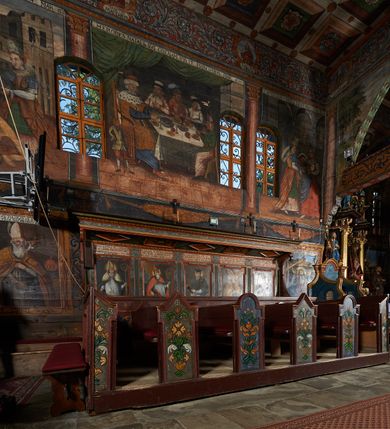 Zdjęcie nr 57: Polichromia ścienna prezbiterium pokrywa wszystkie ściany oraz strop tej części świątyni. 

Polichromia ścienna stropu
Strop zdobiony jest malowanymi kasetonami, w których umieszczone są rozety na różnokolorowych tłach. W centrum ukazane są dwie prostokątne kompozycje, ujęte w ornamentalne ramy. Od wschodu znajduje się Zwiastowanie Zachariaszowi, powyżej inskrypcja: „NE TIMEAS ZACHARIA VXOR TVA PARIET TIBI / FILIVM ET VOCABIS NOMEN EIVS IOANNEM LUCAE 1”. W drugiej kompozycji przedstawiono Nawiedzenie z Najświętszej Marii Panny ze św. Zachariaszem i św. Józefem, powyżej inskrypcja: „EXVLTAVIT IN GAVDIO INFANS IN VTERO MEO LUCAE 1”. 

Polichromia ścienna ścian prezbiterium
Dekoracje ścian o formie pasowej. W dolnej kondygnacji malowane iluzjonistycznie portrety świętych węgierskich w ornamentalnych ramach. Postacie ukazane do wysokości kolan, zwrócone trzy czwarte z odpowiednimi im atrybutami w dłoniach. Portrety opatrzone u góry łacińskimi opisami. Na ścianie północnej galerię otwiera wizerunek króla Stefana z napisem: „S(ANCTVS) STEPHANVS REX VNGARIAE, REGNVM SVVM DEIPARAE / DONAVIT OBIIT. 1038. 20 AVG(VSTVS) SEP. ALBERE 9.”. Następnie ukazani są kolejno: św. Emeryk „S(ANCTVS) EMERIGVS DVX VNGARIAE VT VIRGO MANERET, / A. CAELO PERSVASVS OBIIT. 1032. 5 nou. Sen. Albdvewas”, św. Władysław: „S(ANCTVS) LADISLAVS REX UNGARIAE ROSARIO ENSI OBVO/LUTO PVGNARE SOLITVS OBIIT 1097. 27.  iun. Sep. varad.”. Po drugiej stronie prezbiterium umieszczone są cztery obrazy świętych o tych samych wymiarach, również opatrzone napisami. Od lewej strony kolejno: św. Salomon „S(ANCTVS) SALOMON REX VNGARIAE DEIN EREMITA VITAE / AVSTERITATE FLORVIT OBIIT 1077. 28. Sept. Sep. Pold. in Idria”, św. Kazimierz: „S(ANCTVS) CASIMIRVS ELECTVS REX VNGARIAE AMORE / SARVANDAE VIRGINITATIS OBIIT 1484 4. MARTII.”, św. Dawid: „S(ANTCVS) DAVID REX SCOTIAE, FILIVS S(ANCTA) MARGA/RITAE VNGARA MATRE NATAE OBIIT 1153”, św. Ludwik: „S(SANCTVS) LVDOVICVS TOLOSANVS EP. E MARIA / REGIS VNG. FILIA NATVS OBIIT 1297 19 Aug(ustvs)”. Cykl ten kończy przy ścianie tęczowej przedstawienie św. Gintera „S(ANCVS) GVNTHERVS EREM. S(ANCTVS) STEPHANI REGIS / VNGARIAE COGNATVS OBIIT 1045 9. oct.”. Dodatkowo w obrazy wpisane są zacheuszki w formie równoramiennych krzyży ujętych w medaliony utworzone z wieńca. W zamknięciu prezbiterium przedstawienia diabłów, a od zachodu pod amboną czyściec.

Kondygnacja druga o podziałach architektonicznych u dołu wydzielona cokołem, dekorowanym złotymi girlandami na czarnym tle. Prostokątne pola wydzielone za pomocą malowanych iluzjonistycznie kolumn korynckich dźwigających architraw zdobiony stylizowanym kimationem jońskim. Powyżej fryz wypełniony wicią akantową, pomiędzy którą wplecione są kartusze z przedstawieniami świętych. W polach, pomiędzy kolumnami wielofigurowe kompozycje ze scenami z życia św. Jana Chrzciciela: Głos wołającego na pustyni „TV QVIS ES VOX CLAMANTIS IN DESERTO IOANN(IS) 1.”, Oto Baranek Boży „ECCE AGNVS DEI ECCE QVI TOLLIT PECCATVM MVNDI IOANN. IMÕ.”, Chrzest Jezusa w Jordanie „IESVS BAPTISTAVS EST A IONNE IN IORDANE MARCI. 1.”, Św. Jan Chrzciciel napomina Heroda „DICEBAT IOANNES HERODI NON LICET TIBI HABERE VXOREM FRATRIS TVI. MARCI 6,19.”, Św. Maria Magdalena pokutująca na pustyni, Św. Jan Chrzciciel na pustyni, Św. Jan Chrzciciel wtrącony do więzienia „HERODES TENVIT IONNEM ET VINXIT EVM IN CARCERE MAR 67o”, Kat podaje głowę św. Jana Chrzciciela Salome „DECOLLAVIT EVM IN CARCERE ET DEDIT CAPVT PVELLAE MAR.6.(?)”, Uczta Heroda „HERODES NATALIS SVI COENAM FECIT PRINCIPIBVS MAR. 6 10.”, Salome podaje głowę św. Jana Chrzciciela matce „CAPVT EIVS PVELLA DEDIT MATRI SVE M. 61”. 

W ostatniej, trzeciej strefie, umieszczonej w partii fryzu znajdują się medaliony. Na ścianie tęczowej, następnie na ścianie północnej i południowej ukazani są kolejno: św. Maciej „SA[N]CTVS / MATTHIAS”, Chrystus „IESVS / CHRISTVS”, św. Piotr „SANCTVS / PETRVS”, św. Szymon „SANCTVS / SIMON”, św. Andrzej „SANCTVS / ANDREAS”, św. Jakub Większy „S(ANCTVS) IACOBI / MAIORI”, św. Jan „(?)”, św. Filip „(?)”, św. Bartłomiej „SANCTVS / BARTHOLO/MAVS”, św. Tomasz „SANCTVS / THOMAS”, św. Mateusz „SANCTVS / MATTHAEVS”, św. Jakub Mniejszy „S(ANCTVS) IACOBVS / MINOR” i św. Juda Tadeusz „S(ANCVS) IVDA / THADEVS” na ścianie tęczowej od południa. Na belce tęczowej, od strony prezbiterium w wieńcu laurowym napis: „PICTVM / A[NNO] D[OMINI] 1711”.