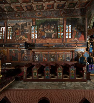 Zdjęcie nr 60: Polichromia ścienna prezbiterium pokrywa wszystkie ściany oraz strop tej części świątyni. 

Polichromia ścienna stropu
Strop zdobiony jest malowanymi kasetonami, w których umieszczone są rozety na różnokolorowych tłach. W centrum ukazane są dwie prostokątne kompozycje, ujęte w ornamentalne ramy. Od wschodu znajduje się Zwiastowanie Zachariaszowi, powyżej inskrypcja: „NE TIMEAS ZACHARIA VXOR TVA PARIET TIBI / FILIVM ET VOCABIS NOMEN EIVS IOANNEM LUCAE 1”. W drugiej kompozycji przedstawiono Nawiedzenie z Najświętszej Marii Panny ze św. Zachariaszem i św. Józefem, powyżej inskrypcja: „EXVLTAVIT IN GAVDIO INFANS IN VTERO MEO LUCAE 1”. 

Polichromia ścienna ścian prezbiterium
Dekoracje ścian o formie pasowej. W dolnej kondygnacji malowane iluzjonistycznie portrety świętych węgierskich w ornamentalnych ramach. Postacie ukazane do wysokości kolan, zwrócone trzy czwarte z odpowiednimi im atrybutami w dłoniach. Portrety opatrzone u góry łacińskimi opisami. Na ścianie północnej galerię otwiera wizerunek króla Stefana z napisem: „S(ANCTVS) STEPHANVS REX VNGARIAE, REGNVM SVVM DEIPARAE / DONAVIT OBIIT. 1038. 20 AVG(VSTVS) SEP. ALBERE 9.”. Następnie ukazani są kolejno: św. Emeryk „S(ANCTVS) EMERIGVS DVX VNGARIAE VT VIRGO MANERET, / A. CAELO PERSVASVS OBIIT. 1032. 5 nou. Sen. Albdvewas”, św. Władysław: „S(ANCTVS) LADISLAVS REX UNGARIAE ROSARIO ENSI OBVO/LUTO PVGNARE SOLITVS OBIIT 1097. 27.  iun. Sep. varad.”. Po drugiej stronie prezbiterium umieszczone są cztery obrazy świętych o tych samych wymiarach, również opatrzone napisami. Od lewej strony kolejno: św. Salomon „S(ANCTVS) SALOMON REX VNGARIAE DEIN EREMITA VITAE / AVSTERITATE FLORVIT OBIIT 1077. 28. Sept. Sep. Pold. in Idria”, św. Kazimierz: „S(ANCTVS) CASIMIRVS ELECTVS REX VNGARIAE AMORE / SARVANDAE VIRGINITATIS OBIIT 1484 4. MARTII.”, św. Dawid: „S(ANTCVS) DAVID REX SCOTIAE, FILIVS S(ANCTA) MARGA/RITAE VNGARA MATRE NATAE OBIIT 1153”, św. Ludwik: „S(SANCTVS) LVDOVICVS TOLOSANVS EP. E MARIA / REGIS VNG. FILIA NATVS OBIIT 1297 19 Aug(ustvs)”. Cykl ten kończy przy ścianie tęczowej przedstawienie św. Gintera „S(ANCVS) GVNTHERVS EREM. S(ANCTVS) STEPHANI REGIS / VNGARIAE COGNATVS OBIIT 1045 9. oct.”. Dodatkowo w obrazy wpisane są zacheuszki w formie równoramiennych krzyży ujętych w medaliony utworzone z wieńca. W zamknięciu prezbiterium przedstawienia diabłów, a od zachodu pod amboną czyściec.

Kondygnacja druga o podziałach architektonicznych u dołu wydzielona cokołem, dekorowanym złotymi girlandami na czarnym tle. Prostokątne pola wydzielone za pomocą malowanych iluzjonistycznie kolumn korynckich dźwigających architraw zdobiony stylizowanym kimationem jońskim. Powyżej fryz wypełniony wicią akantową, pomiędzy którą wplecione są kartusze z przedstawieniami świętych. W polach, pomiędzy kolumnami wielofigurowe kompozycje ze scenami z życia św. Jana Chrzciciela: Głos wołającego na pustyni „TV QVIS ES VOX CLAMANTIS IN DESERTO IOANN(IS) 1.”, Oto Baranek Boży „ECCE AGNVS DEI ECCE QVI TOLLIT PECCATVM MVNDI IOANN. IMÕ.”, Chrzest Jezusa w Jordanie „IESVS BAPTISTAVS EST A IONNE IN IORDANE MARCI. 1.”, Św. Jan Chrzciciel napomina Heroda „DICEBAT IOANNES HERODI NON LICET TIBI HABERE VXOREM FRATRIS TVI. MARCI 6,19.”, Św. Maria Magdalena pokutująca na pustyni, Św. Jan Chrzciciel na pustyni, Św. Jan Chrzciciel wtrącony do więzienia „HERODES TENVIT IONNEM ET VINXIT EVM IN CARCERE MAR 67o”, Kat podaje głowę św. Jana Chrzciciela Salome „DECOLLAVIT EVM IN CARCERE ET DEDIT CAPVT PVELLAE MAR.6.(?)”, Uczta Heroda „HERODES NATALIS SVI COENAM FECIT PRINCIPIBVS MAR. 6 10.”, Salome podaje głowę św. Jana Chrzciciela matce „CAPVT EIVS PVELLA DEDIT MATRI SVE M. 61”. 

W ostatniej, trzeciej strefie, umieszczonej w partii fryzu znajdują się medaliony. Na ścianie tęczowej, następnie na ścianie północnej i południowej ukazani są kolejno: św. Maciej „SA[N]CTVS / MATTHIAS”, Chrystus „IESVS / CHRISTVS”, św. Piotr „SANCTVS / PETRVS”, św. Szymon „SANCTVS / SIMON”, św. Andrzej „SANCTVS / ANDREAS”, św. Jakub Większy „S(ANCTVS) IACOBI / MAIORI”, św. Jan „(?)”, św. Filip „(?)”, św. Bartłomiej „SANCTVS / BARTHOLO/MAVS”, św. Tomasz „SANCTVS / THOMAS”, św. Mateusz „SANCTVS / MATTHAEVS”, św. Jakub Mniejszy „S(ANCTVS) IACOBVS / MINOR” i św. Juda Tadeusz „S(ANCVS) IVDA / THADEVS” na ścianie tęczowej od południa. Na belce tęczowej, od strony prezbiterium w wieńcu laurowym napis: „PICTVM / A[NNO] D[OMINI] 1711”.